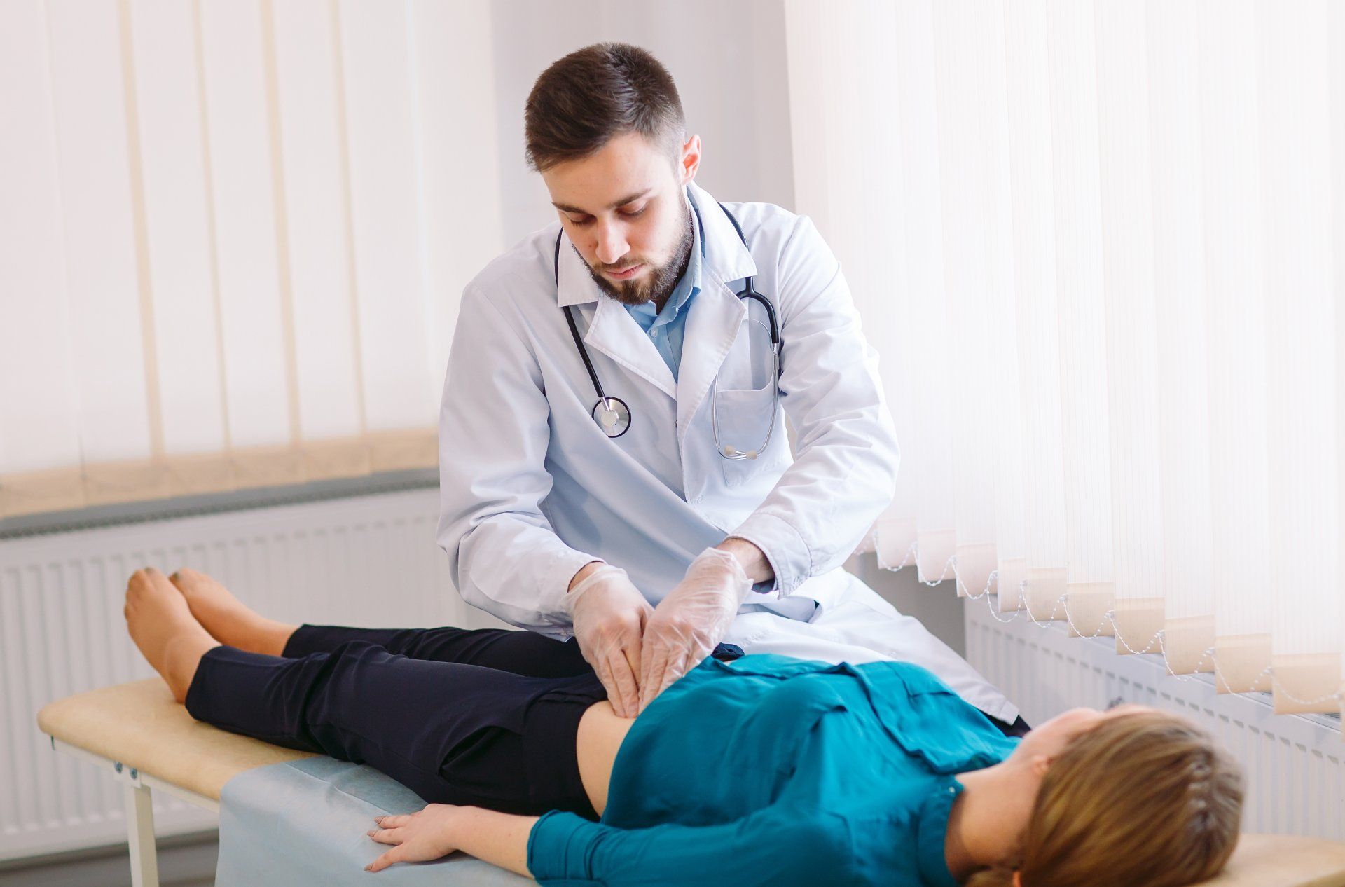 Patient lying on a table while doctor examins their abdomen.