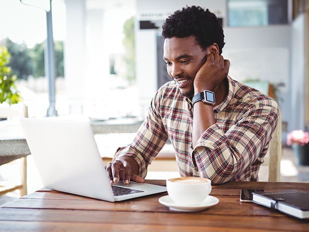 A man is sitting at a table using a laptop computer.