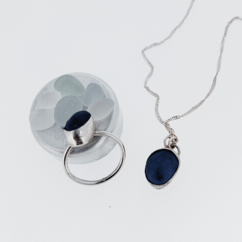 A ring and a necklace are on a white surface
