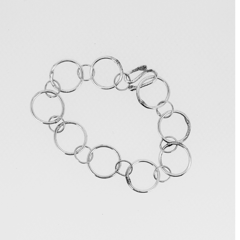 A silver bracelet made of circles on a white background