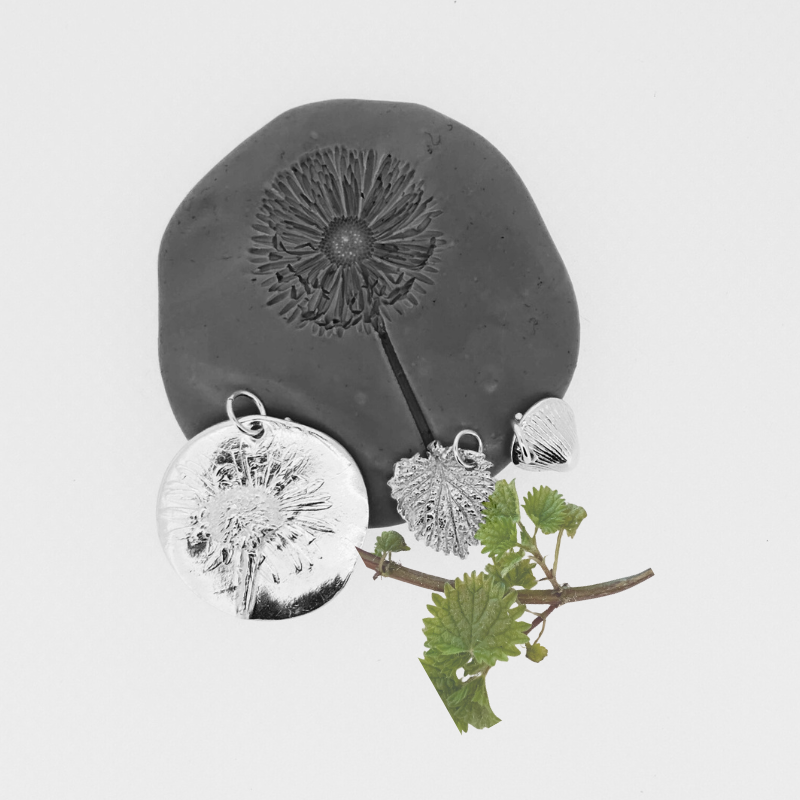 A black and white photo of a dandelion on a piece of clay.