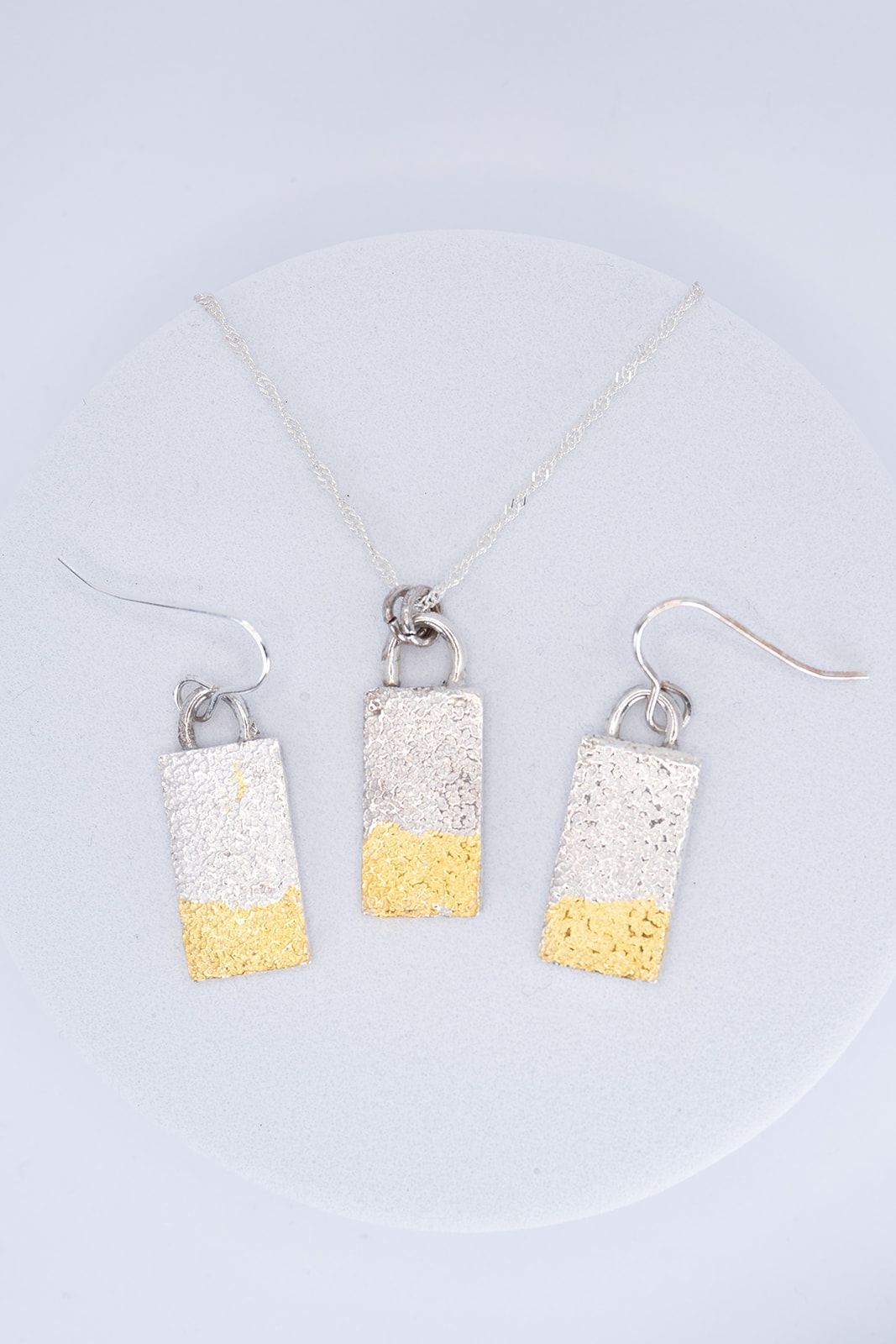 A necklace and earring set is sitting on a white surface.