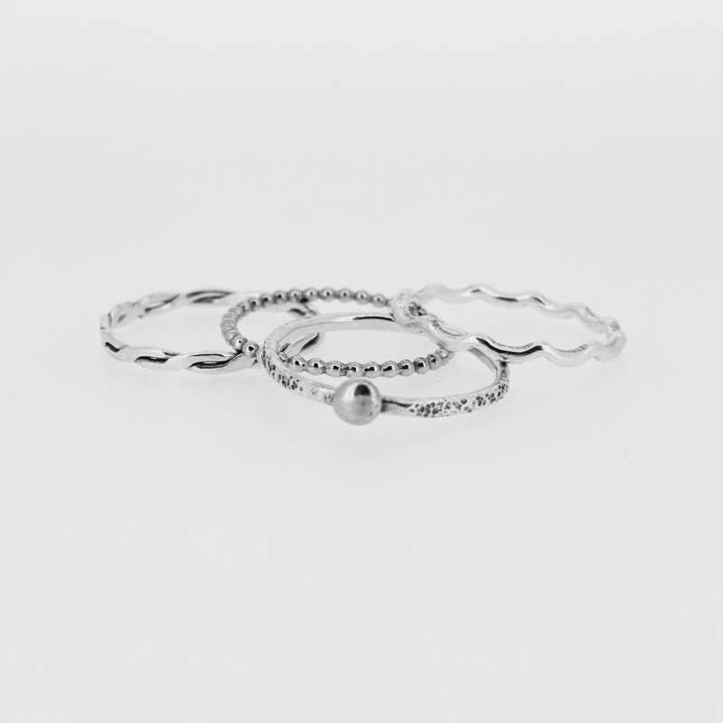 A group of silver rings are stacked on top of each other on a white surface.