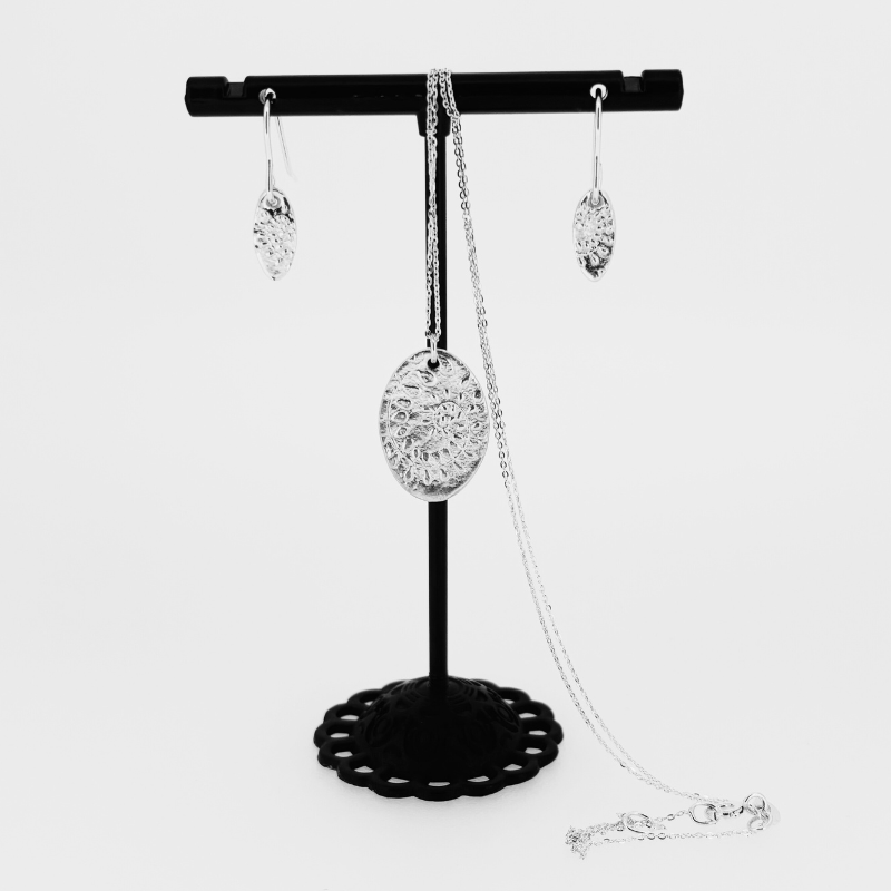 A necklace and earring set on a black stand
