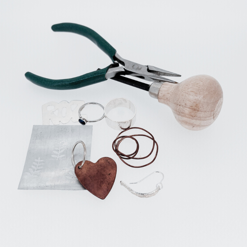 A pair of pliers sits next to a heart shaped keychain