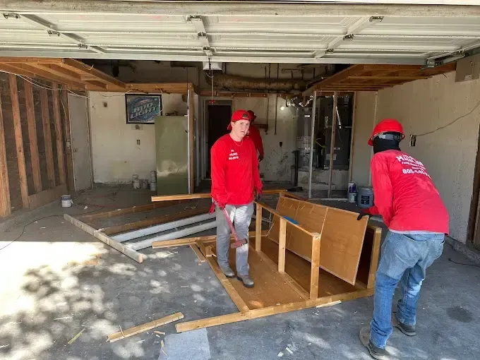 Two men in red shirts are working in a garage.