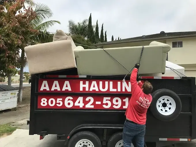 A man is loading a couch onto a aaa hauling trailer.