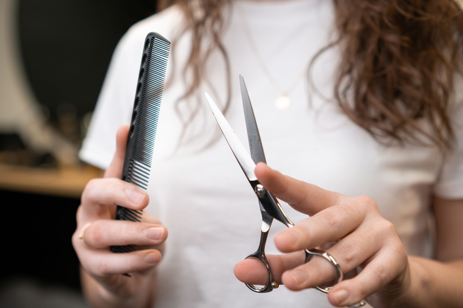 Person holding hair comb and scissors, preparing to cut hair.