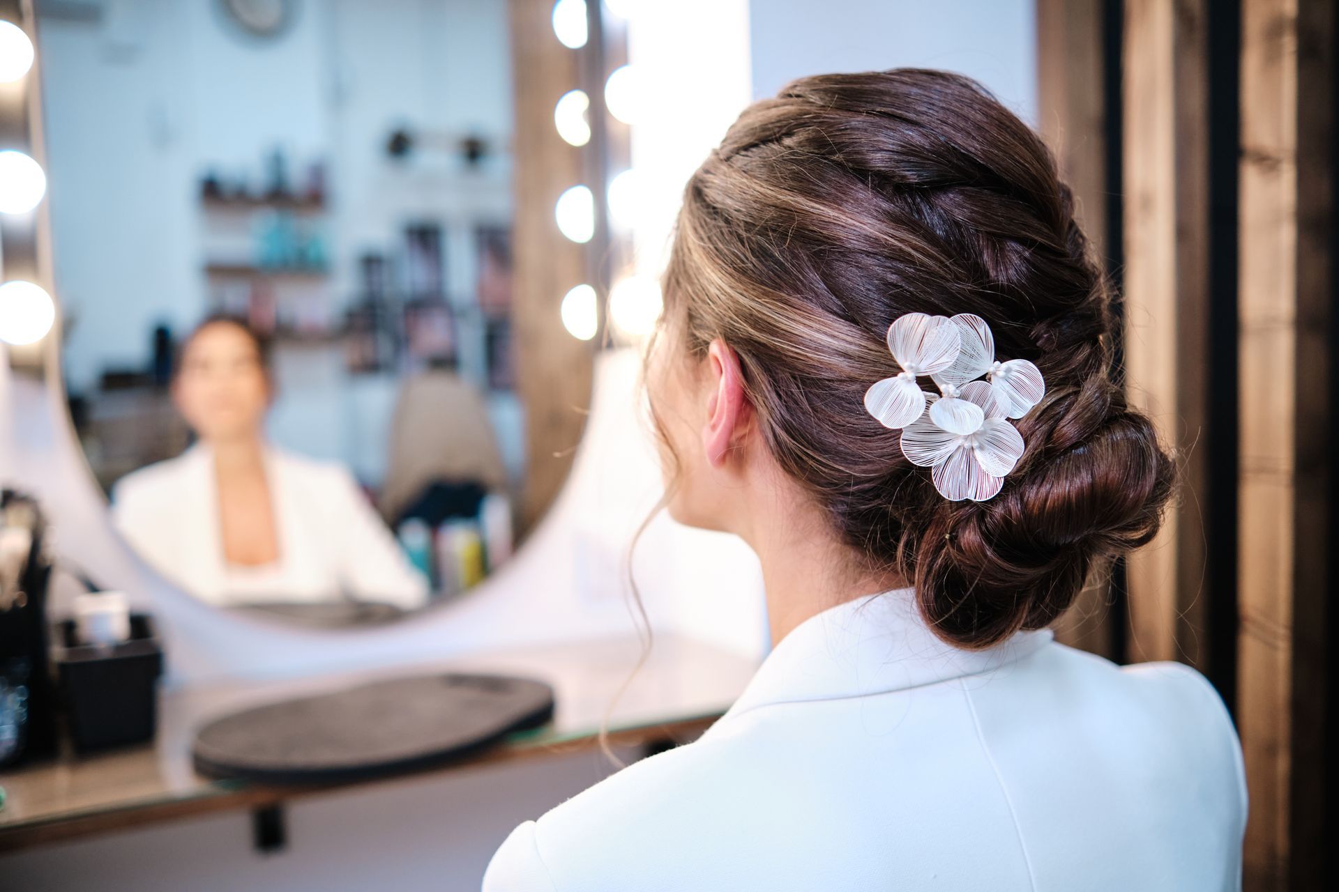 Woman with updo hairstyle and hair accessory looking at herself in a mirror.