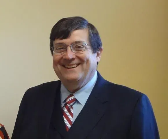 A man in a suit and tie smiles for the camera