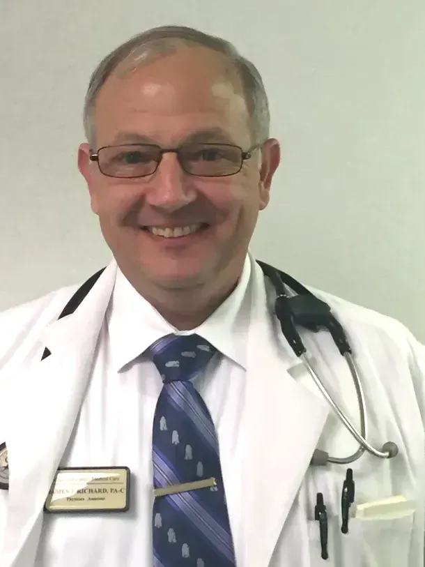 A smiling doctor wearing a white coat and tie