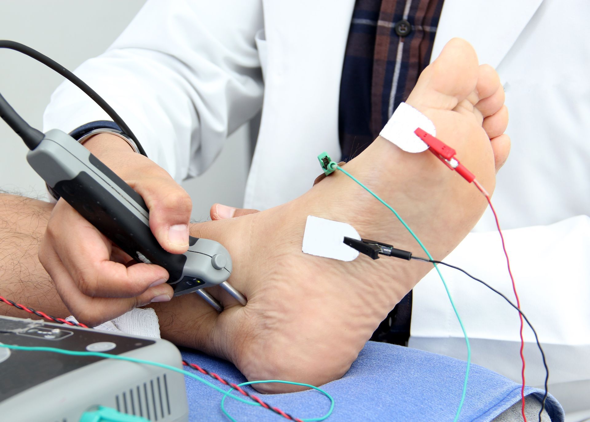 A doctor is examining a patient 's foot with electrodes attached to it