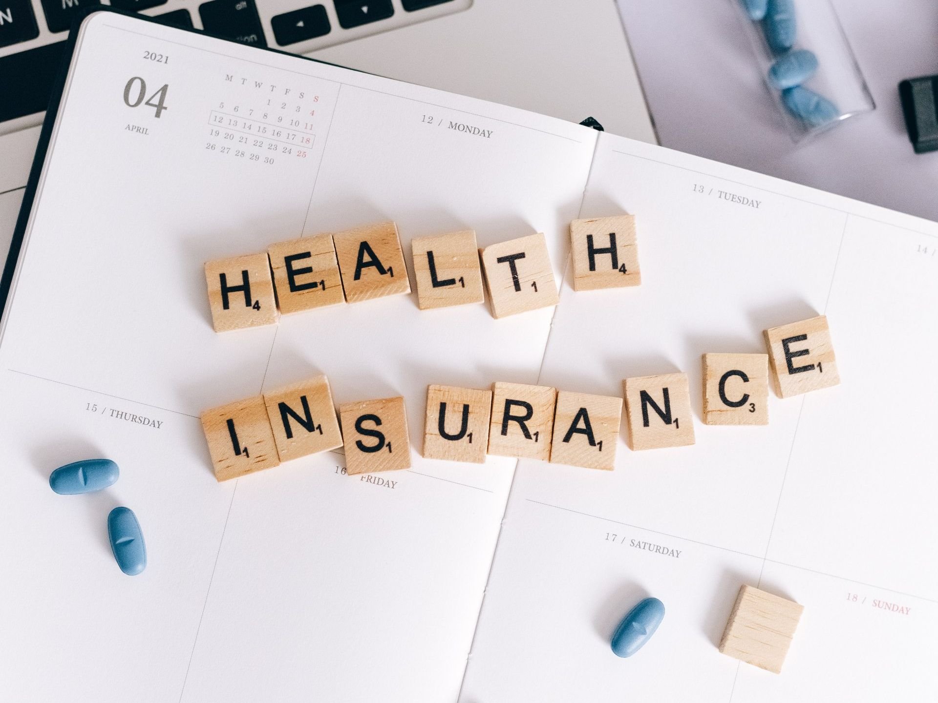 The word health insurance is written in scrabble blocks on a calendar.