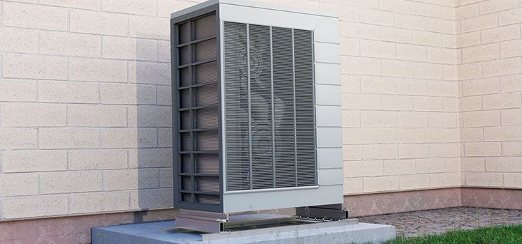 A large air conditioner is sitting outside of a brick building.