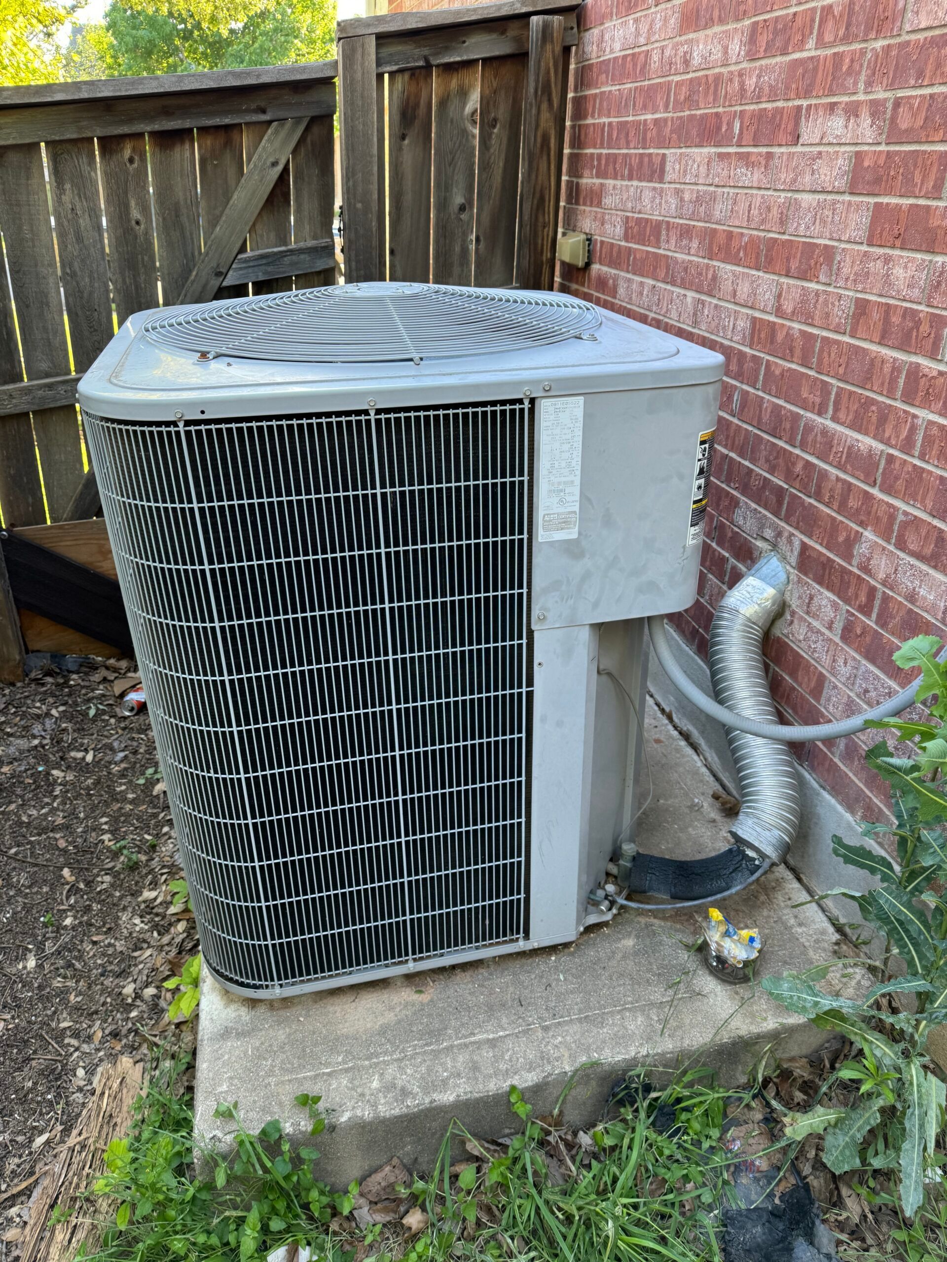 An air conditioner is sitting on the side of a brick building.