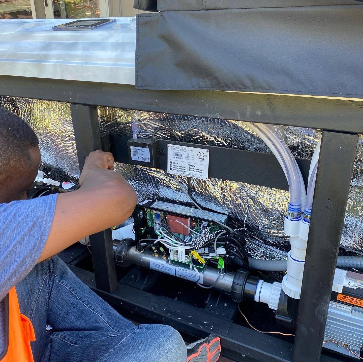 A man in an orange vest is working on a machine.