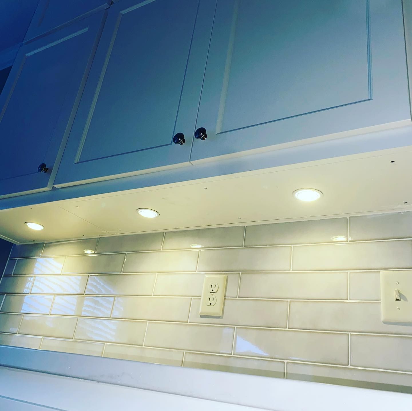 A kitchen with white cabinets and a white brick wall