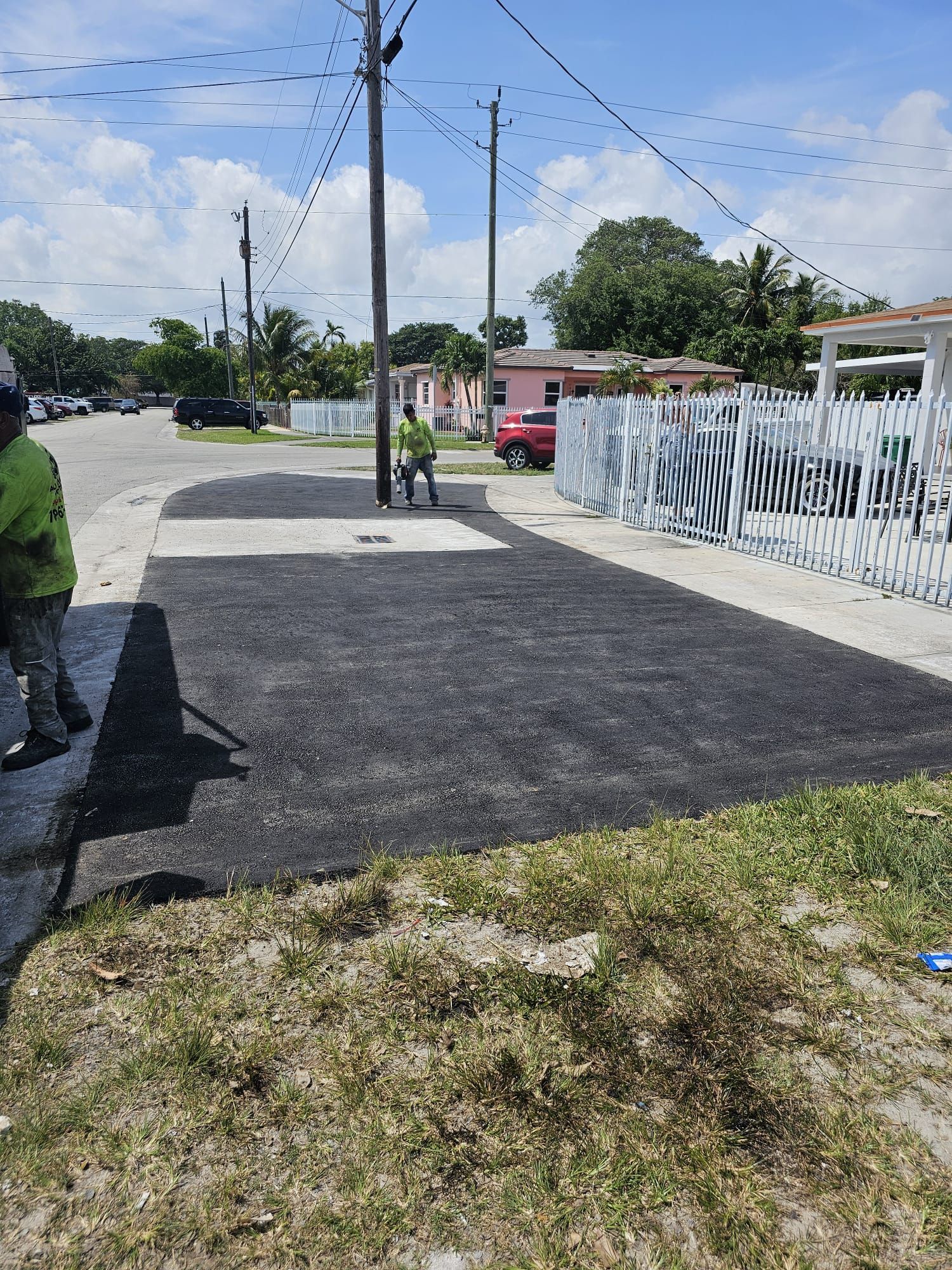 An asphalt driveway leading to a house, featuring a smooth, dark surface with neatly defined edges and a subtle sheen.
