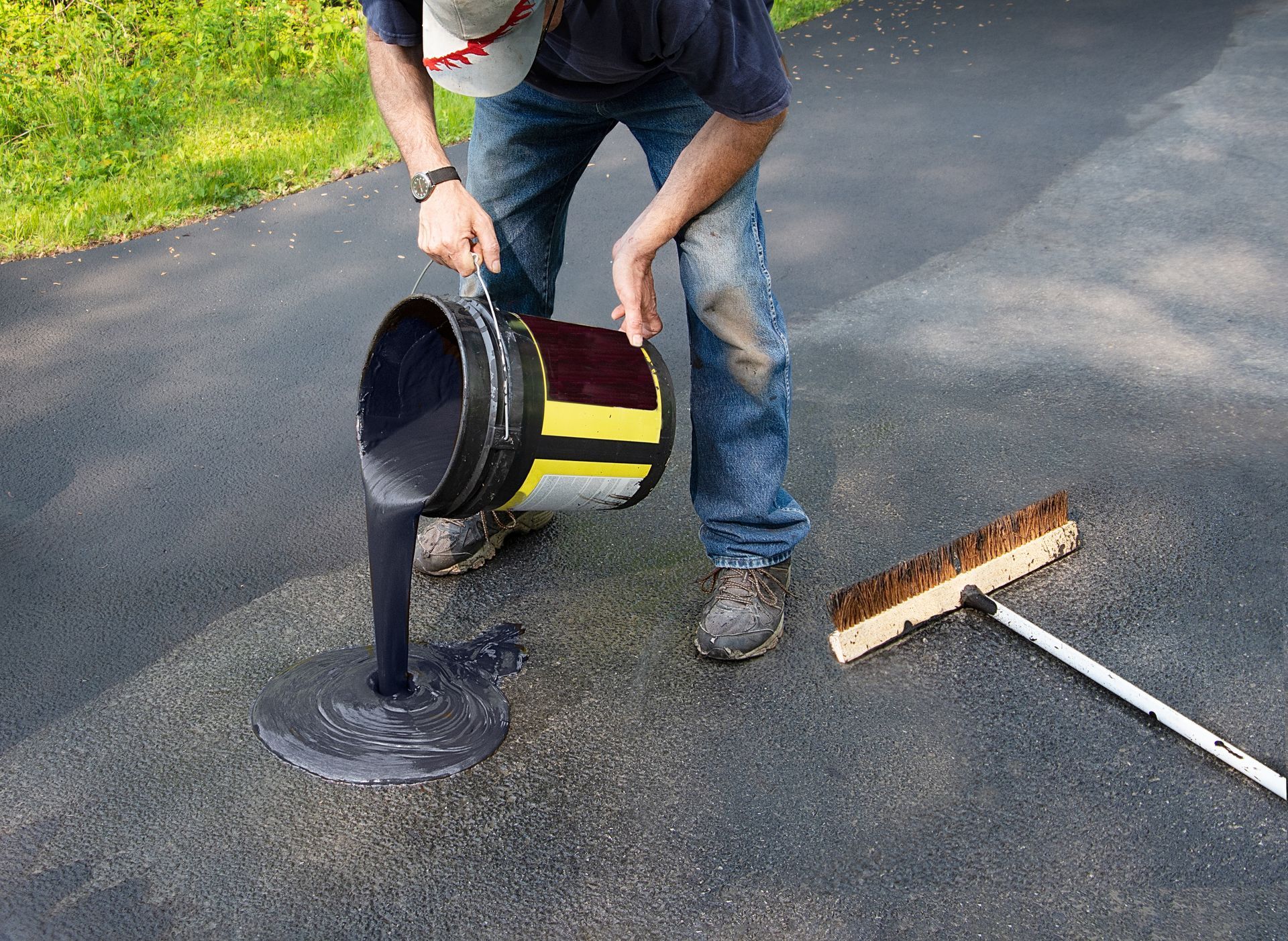 Worker pouring hot asphalt onto a driveway for resealing, ensuring a smooth and durable surface.