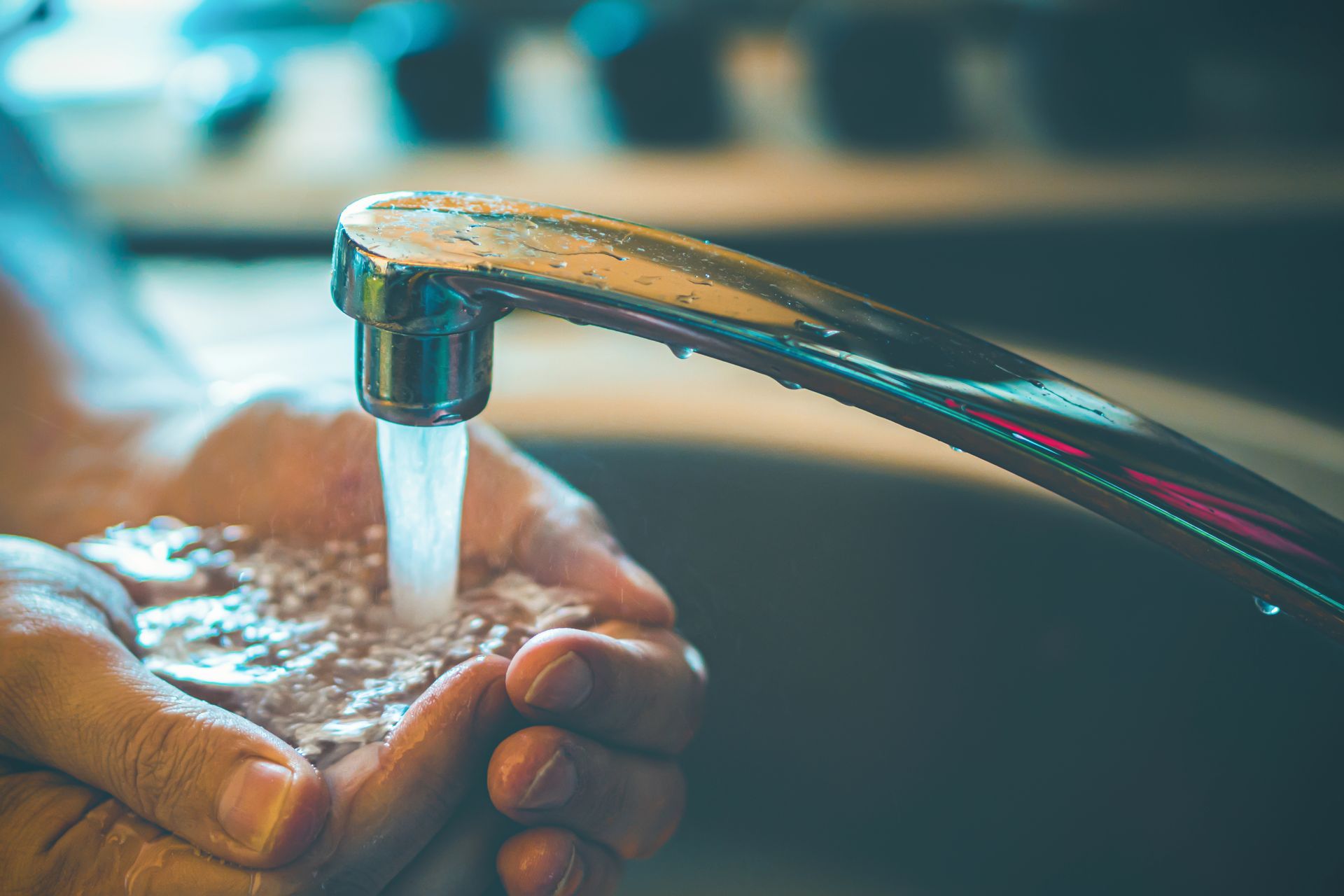mani di un uomo che beve dal rubinetto della cucina