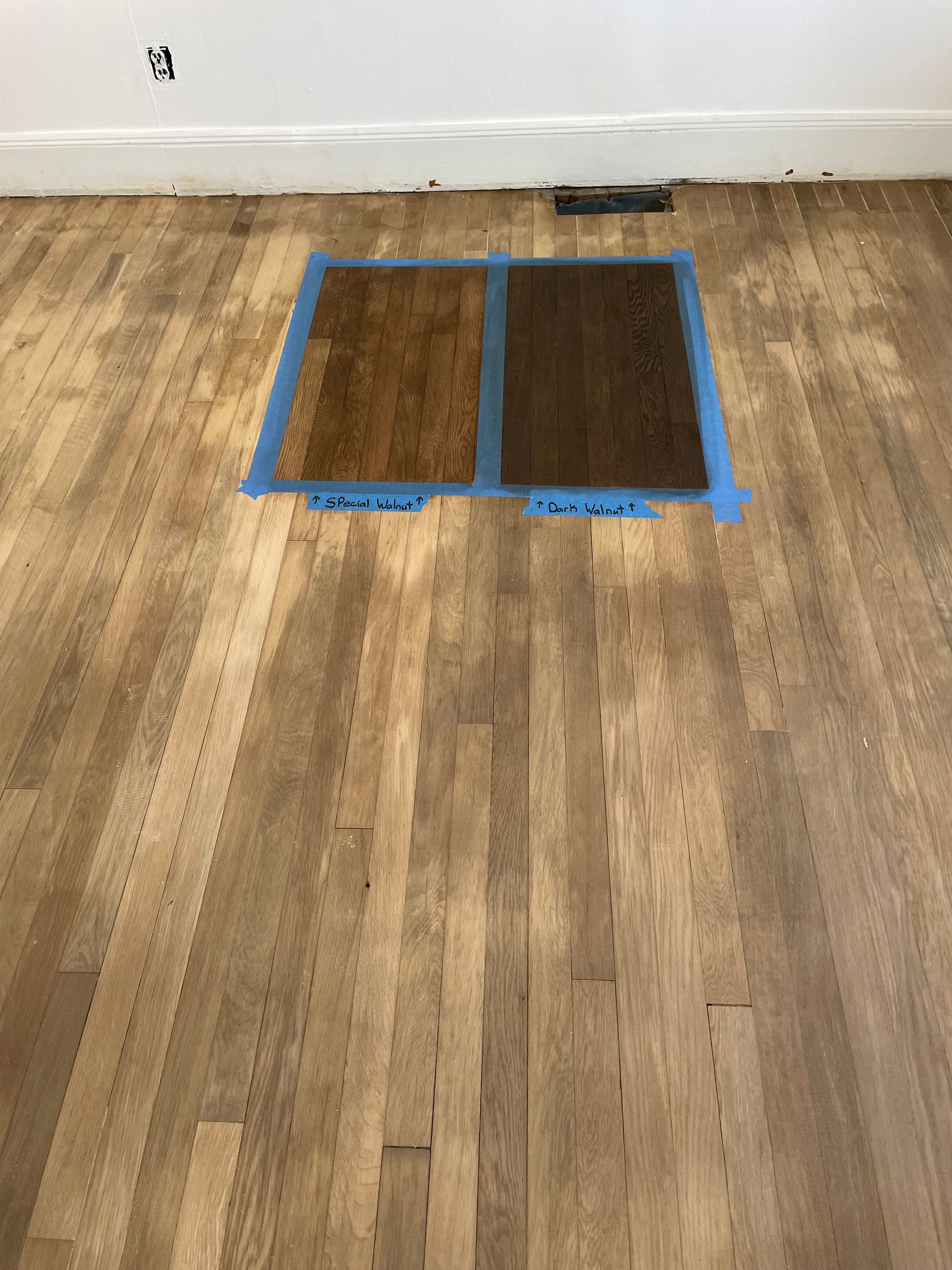 A wooden floor with two pieces of tape on it.
