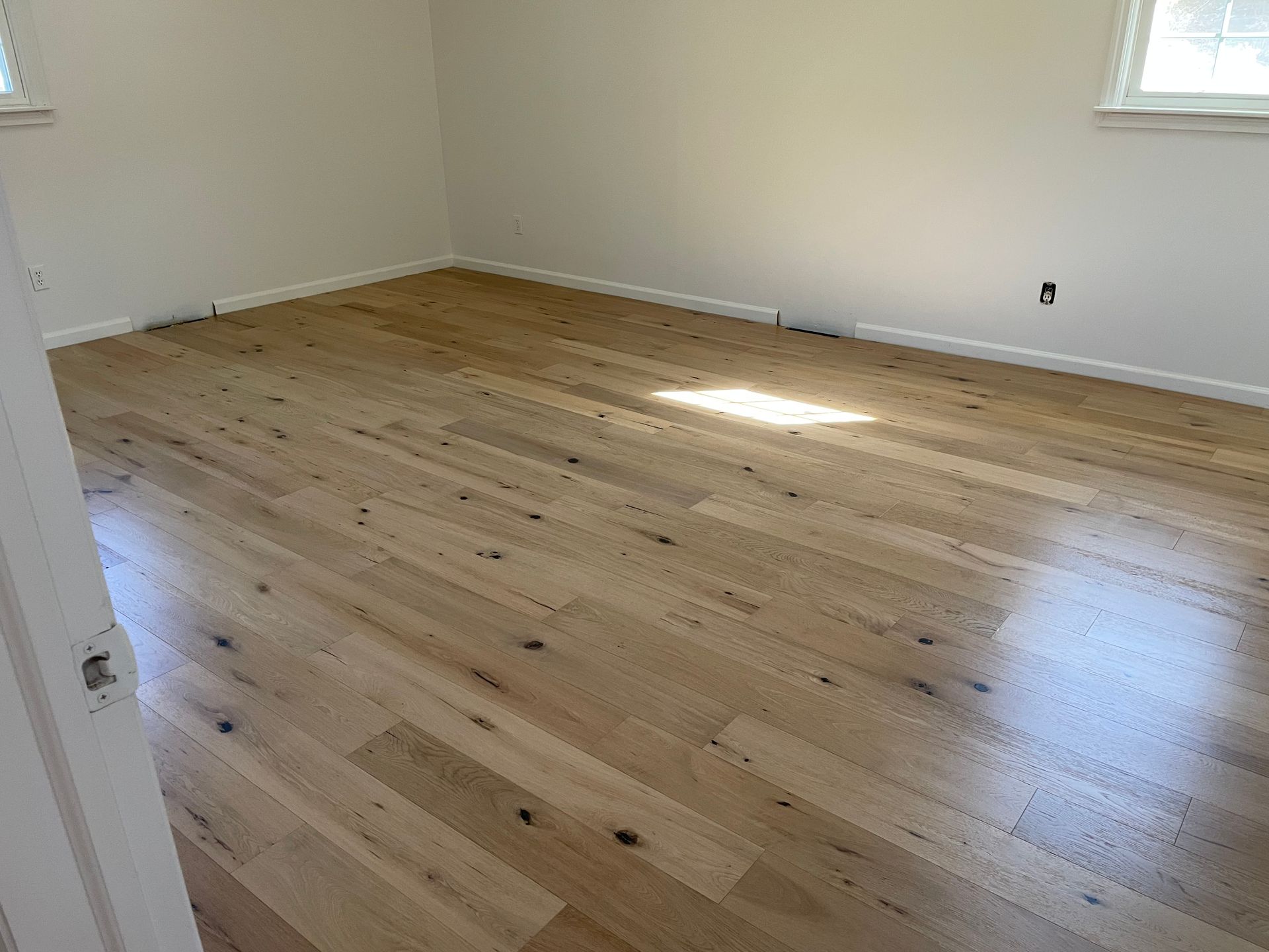 A bedroom with hardwood floors and white walls.