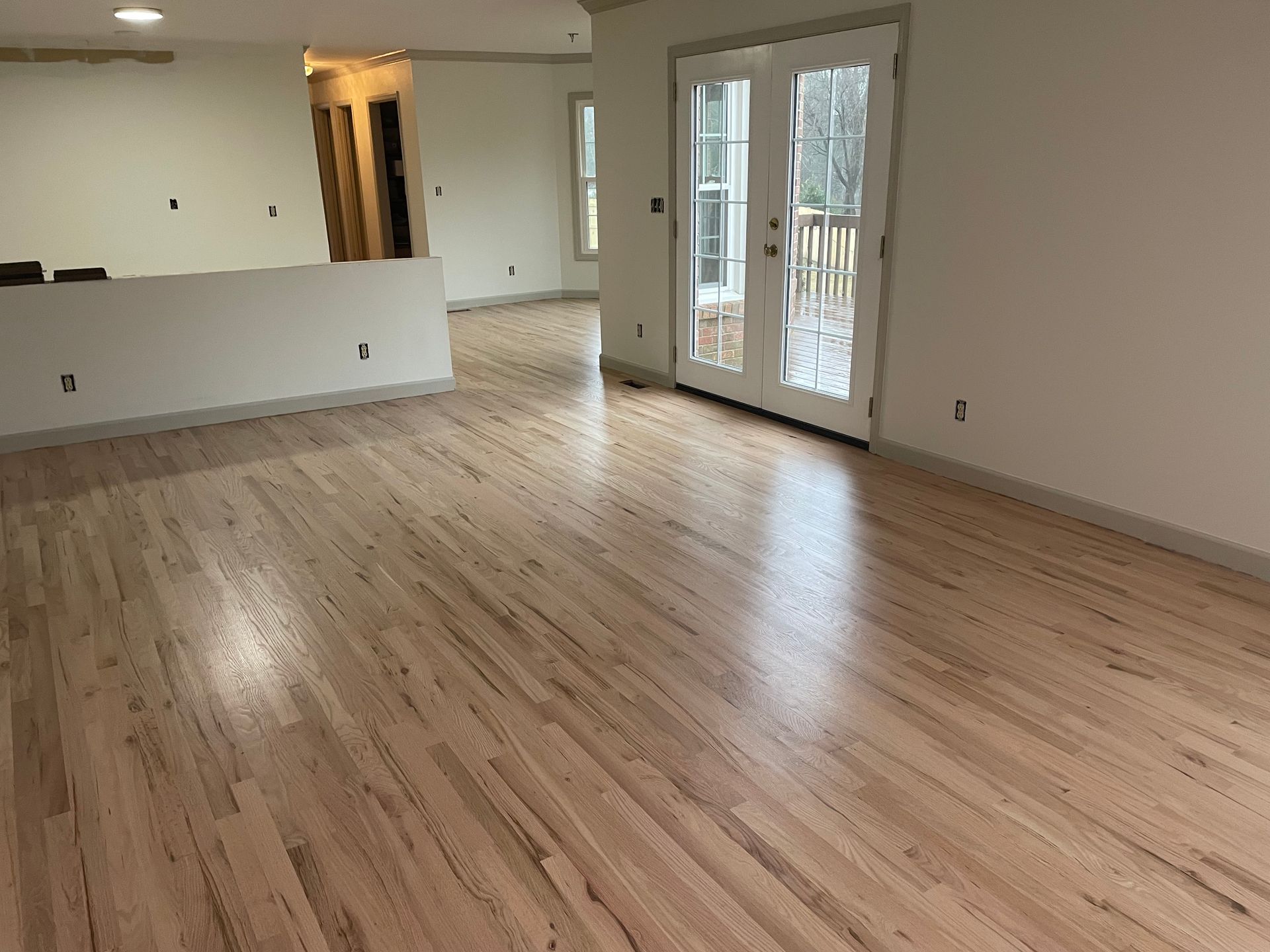 An empty living room with hardwood floors and white walls