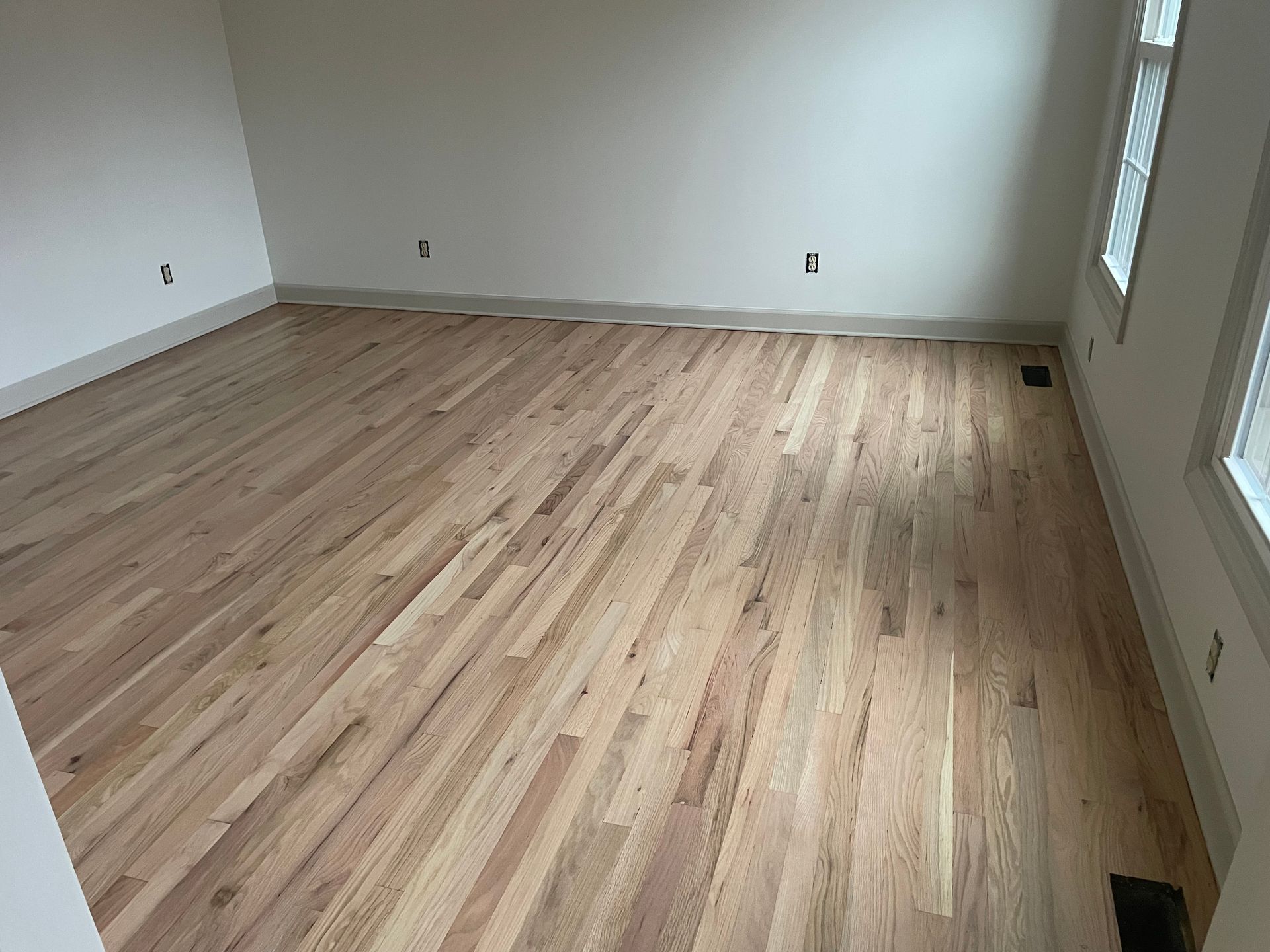 An empty room with hardwood floors and white walls.