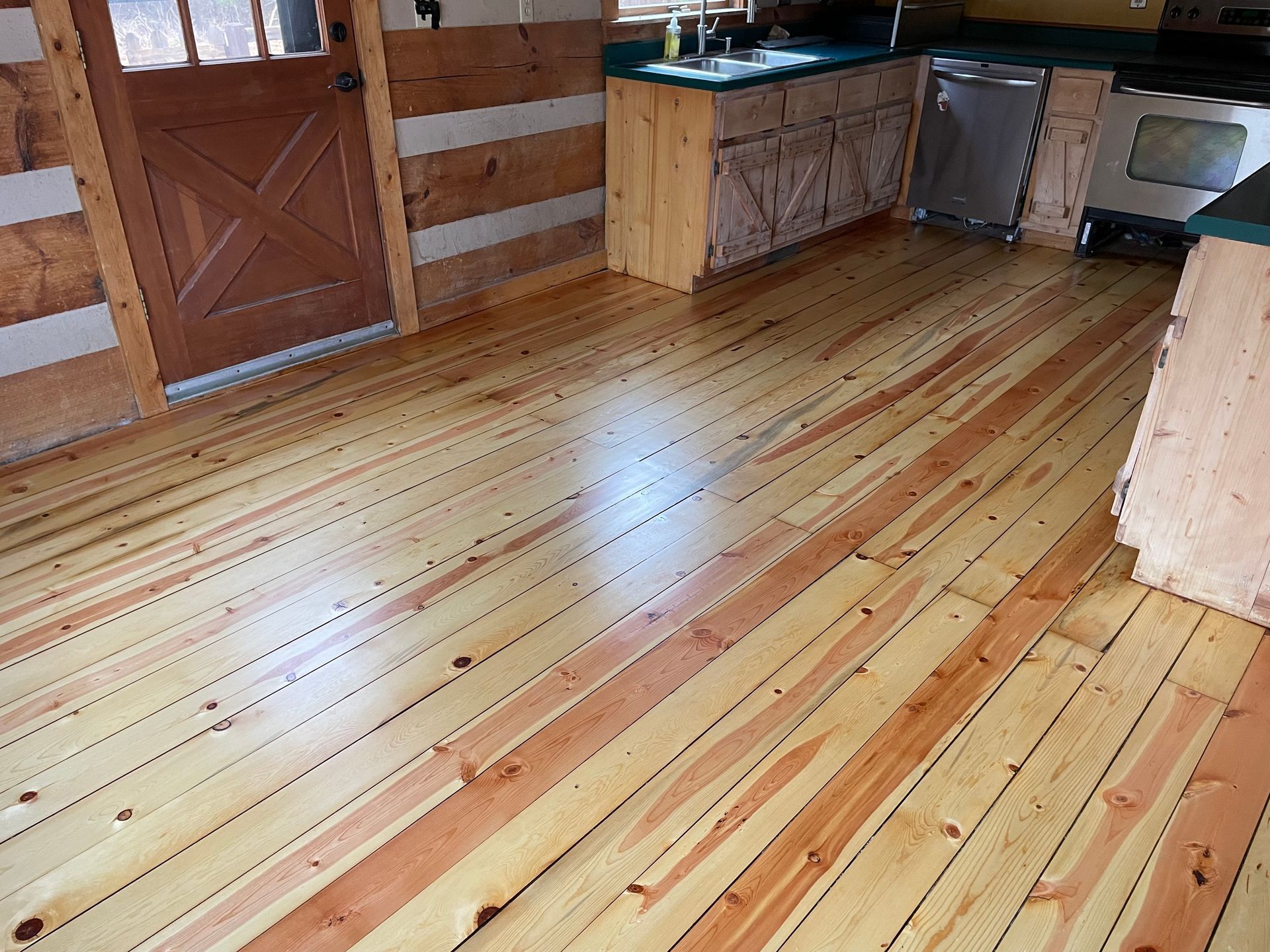 A kitchen with a wooden floor and a wooden door