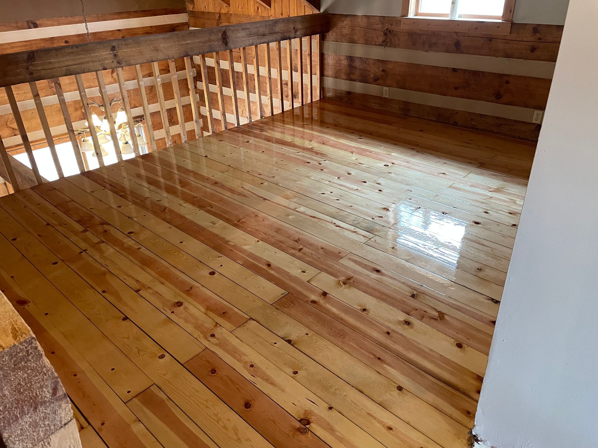 A room with wooden floors and a balcony in a log cabin.