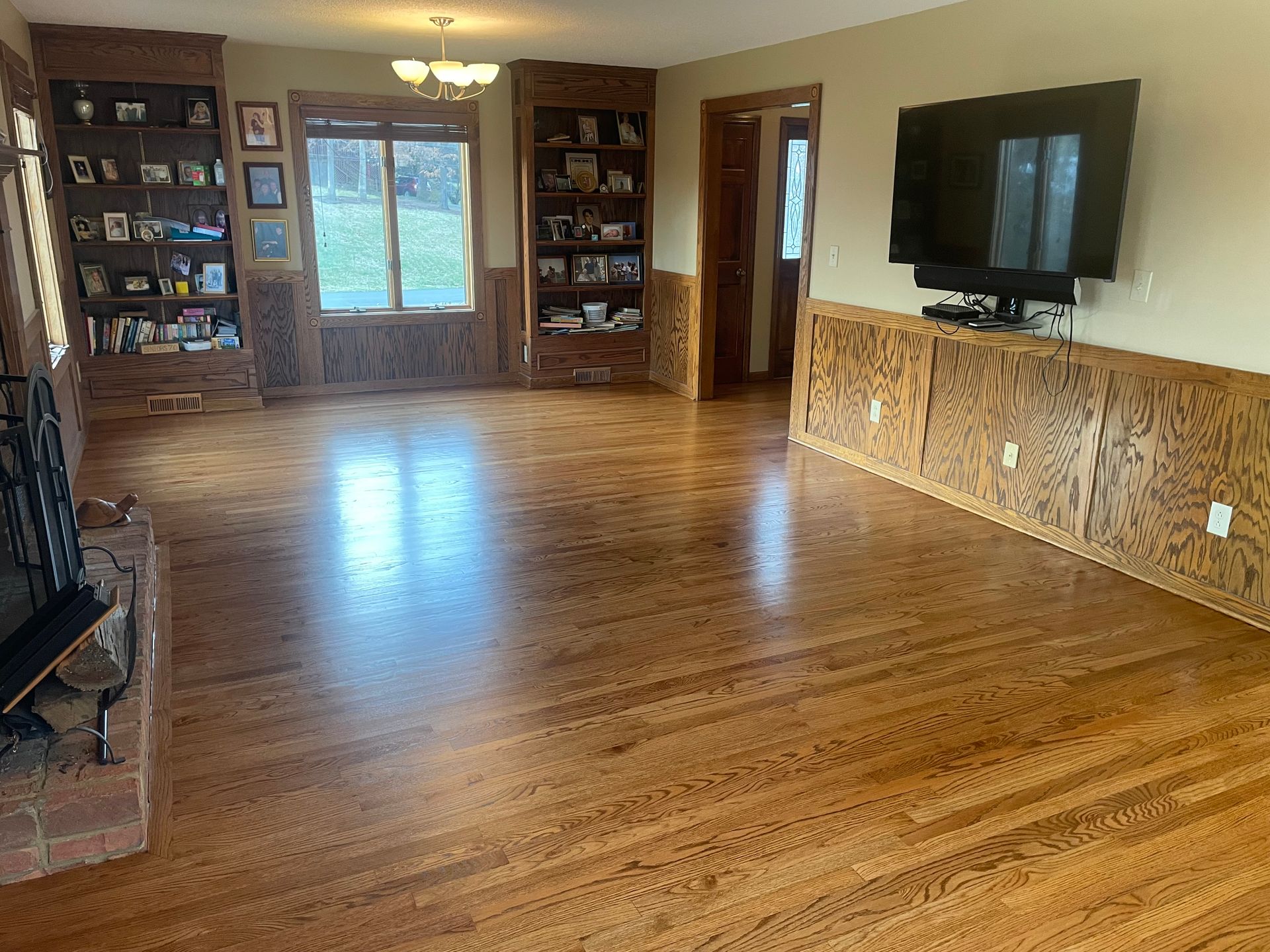 A living room with hardwood floors , a fireplace and a flat screen tv.