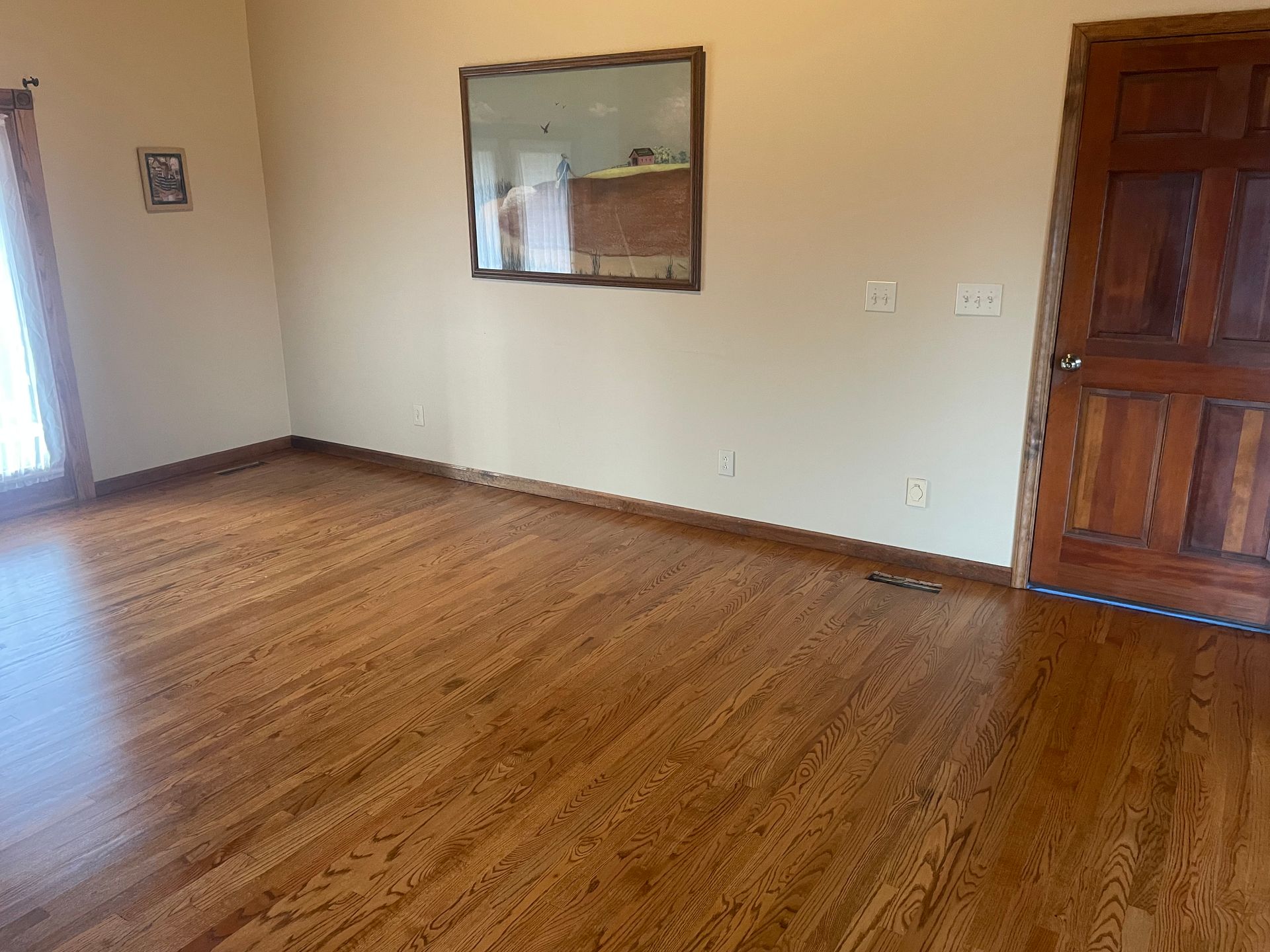 A living room with hardwood floors and a mirror on the wall.