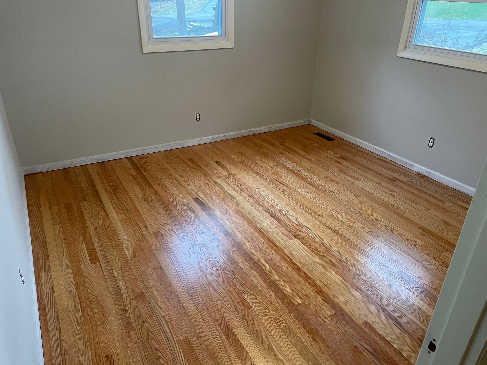 An empty room with hardwood floors and a window.