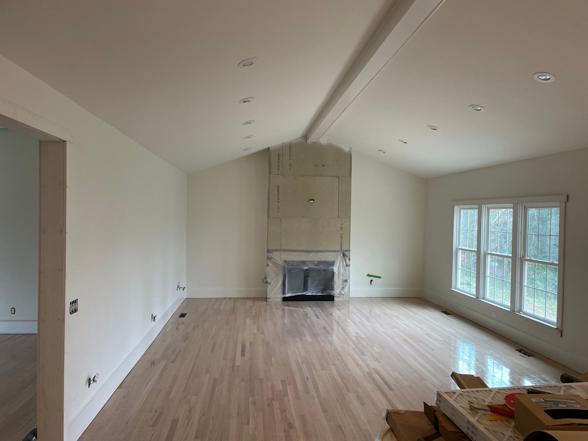 An empty living room with hardwood floors and a fireplace