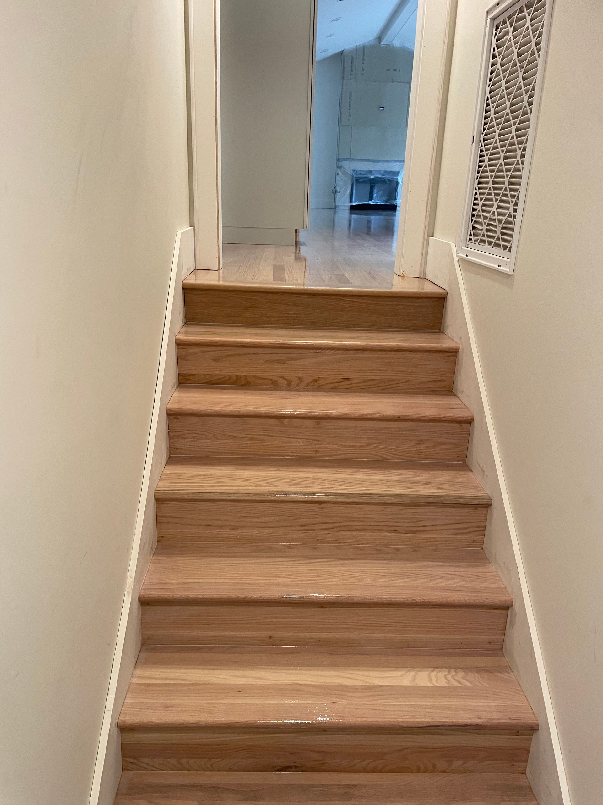 A set of wooden stairs leading up to a hallway in a house.