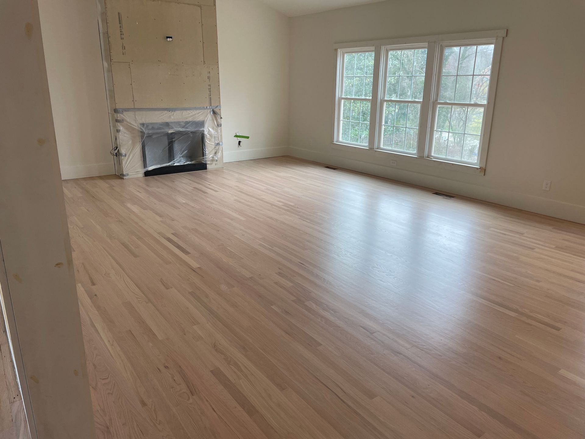 An empty living room with hardwood floors and a fireplace.