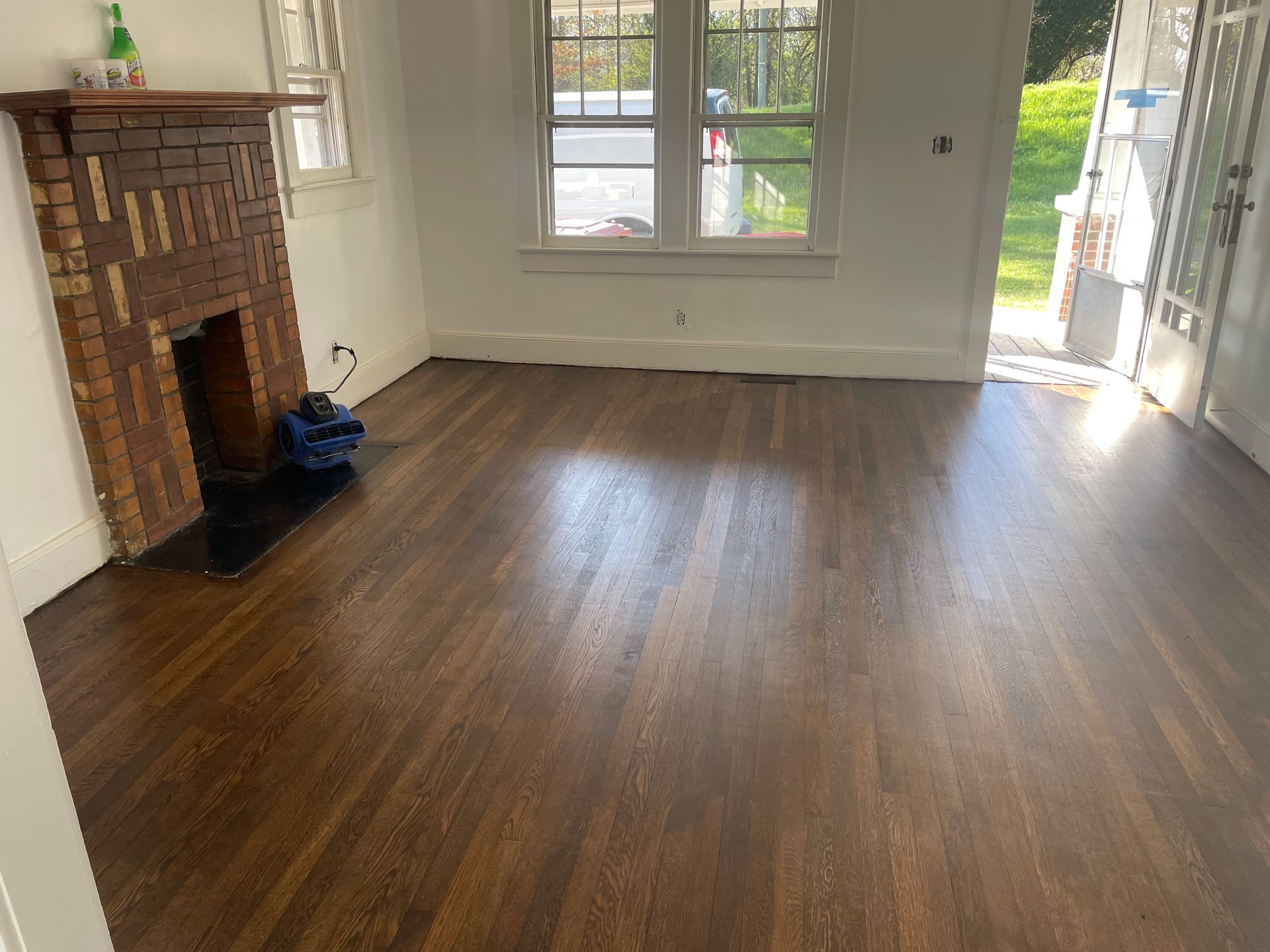 An empty living room with hardwood floors and a fireplace.
