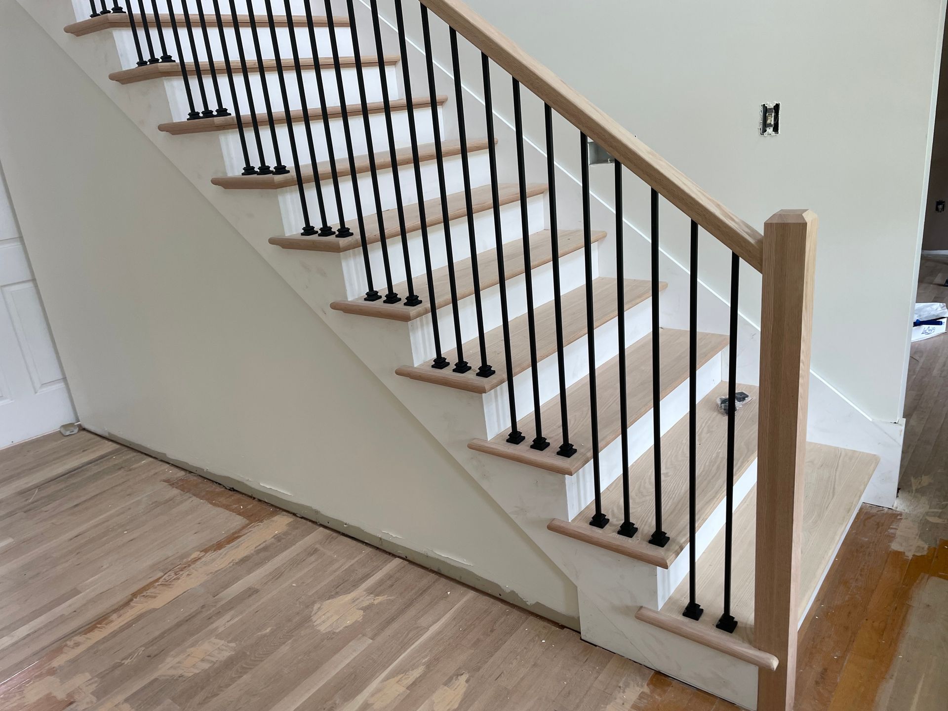 A staircase with white steps and black railing in a house.