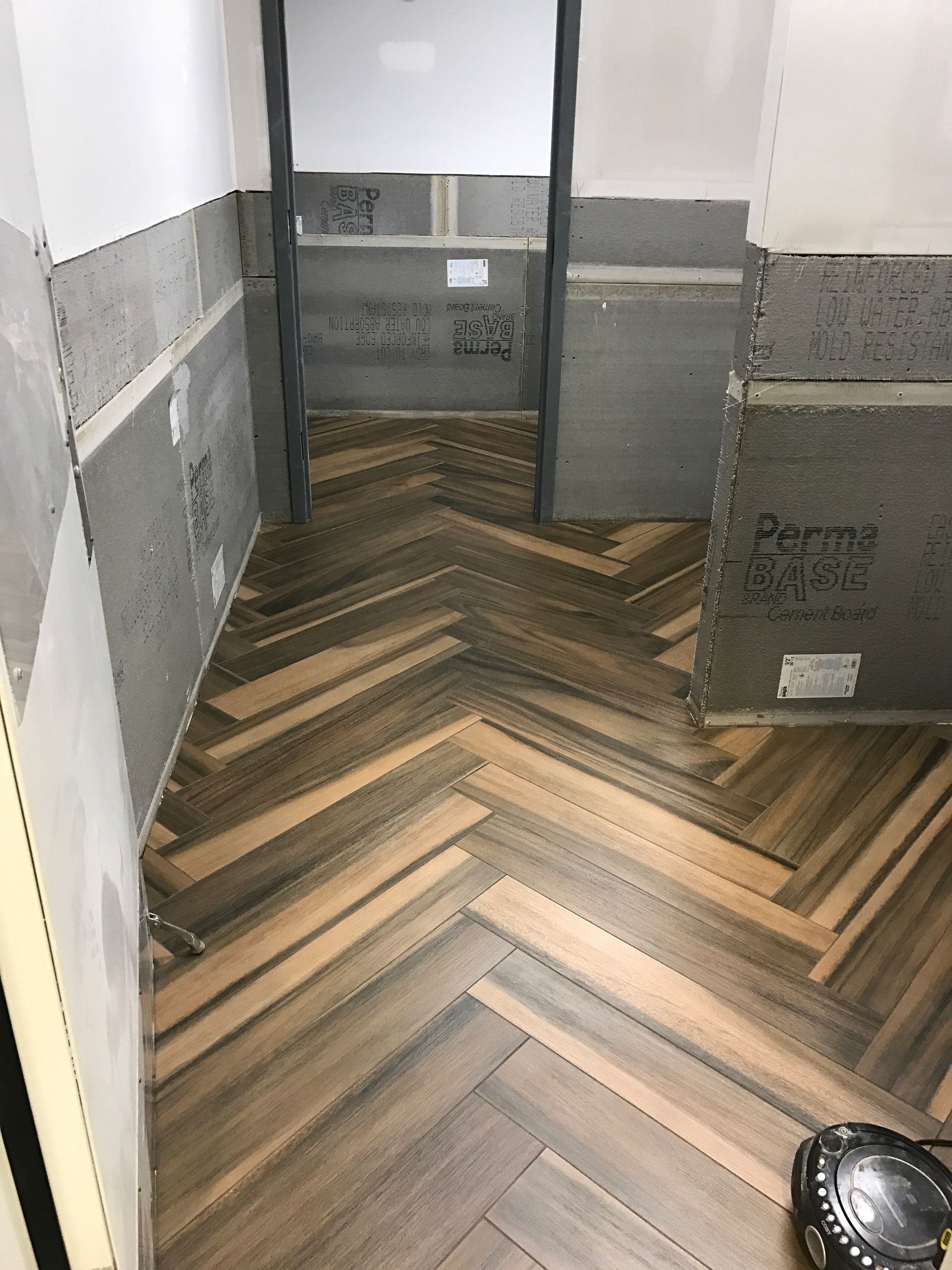 A bathroom with a wooden floor in a herringbone pattern.