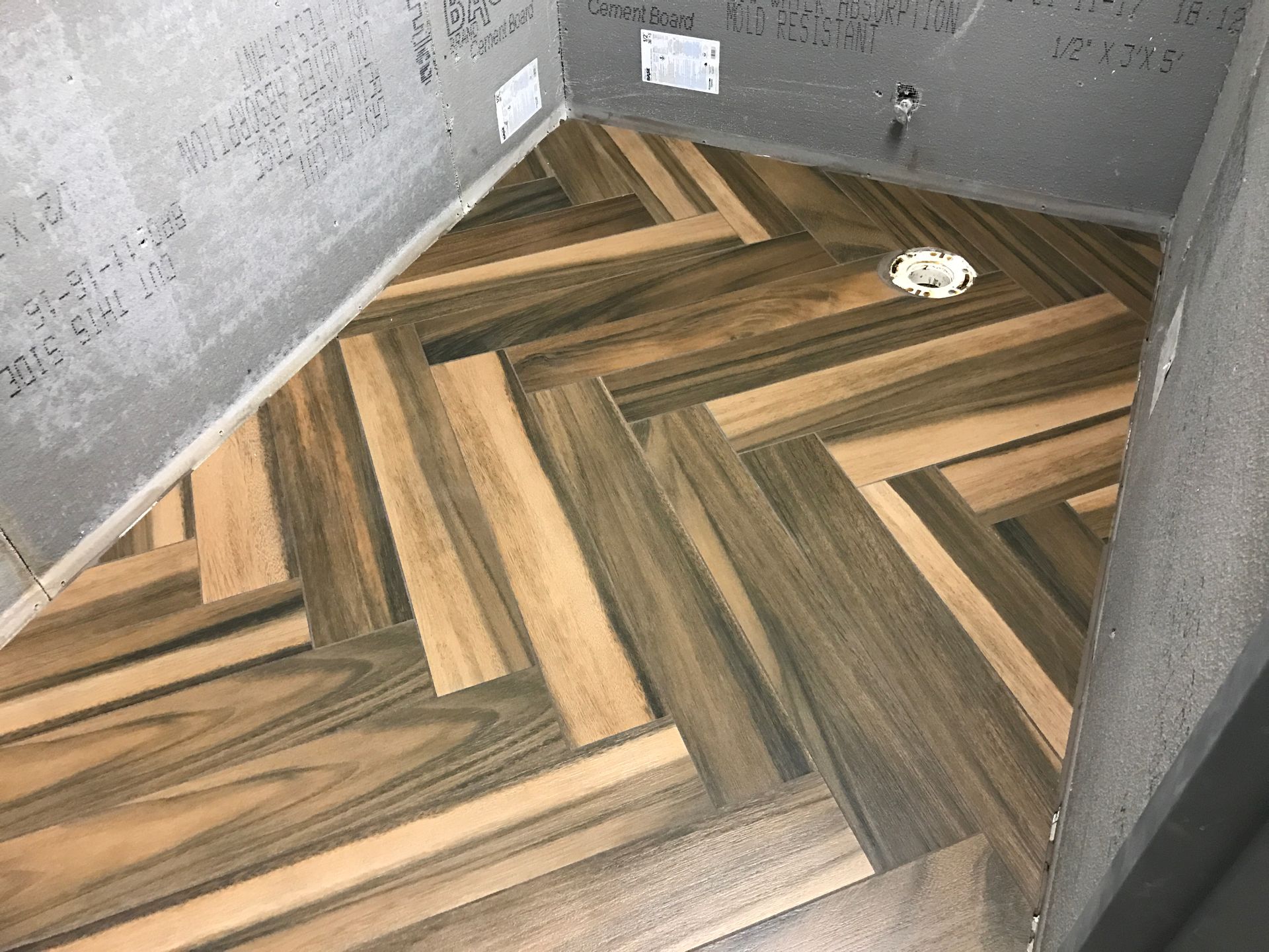 A bathroom with a wooden floor in a herringbone pattern.