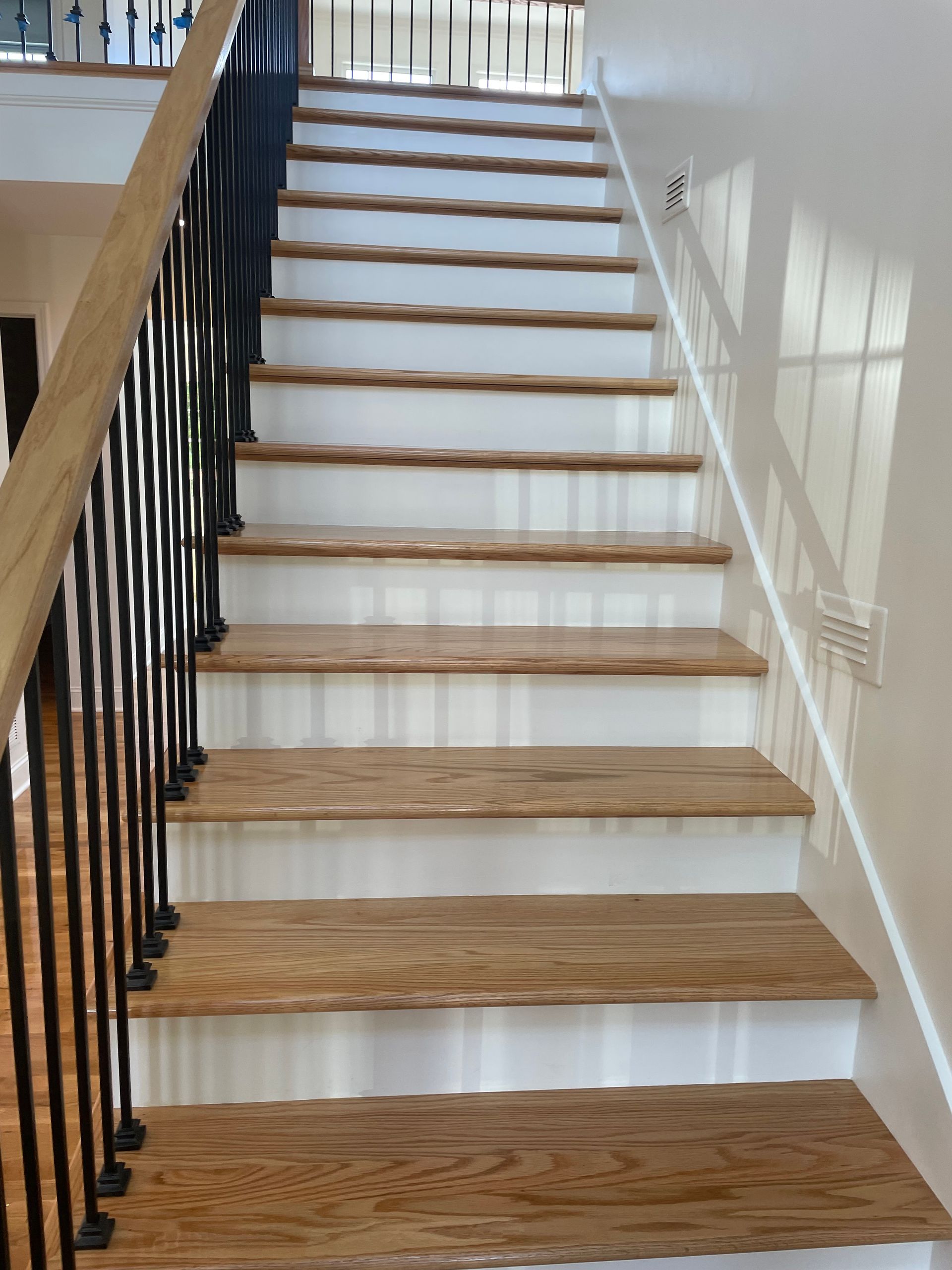 A wooden staircase with white steps and a black railing