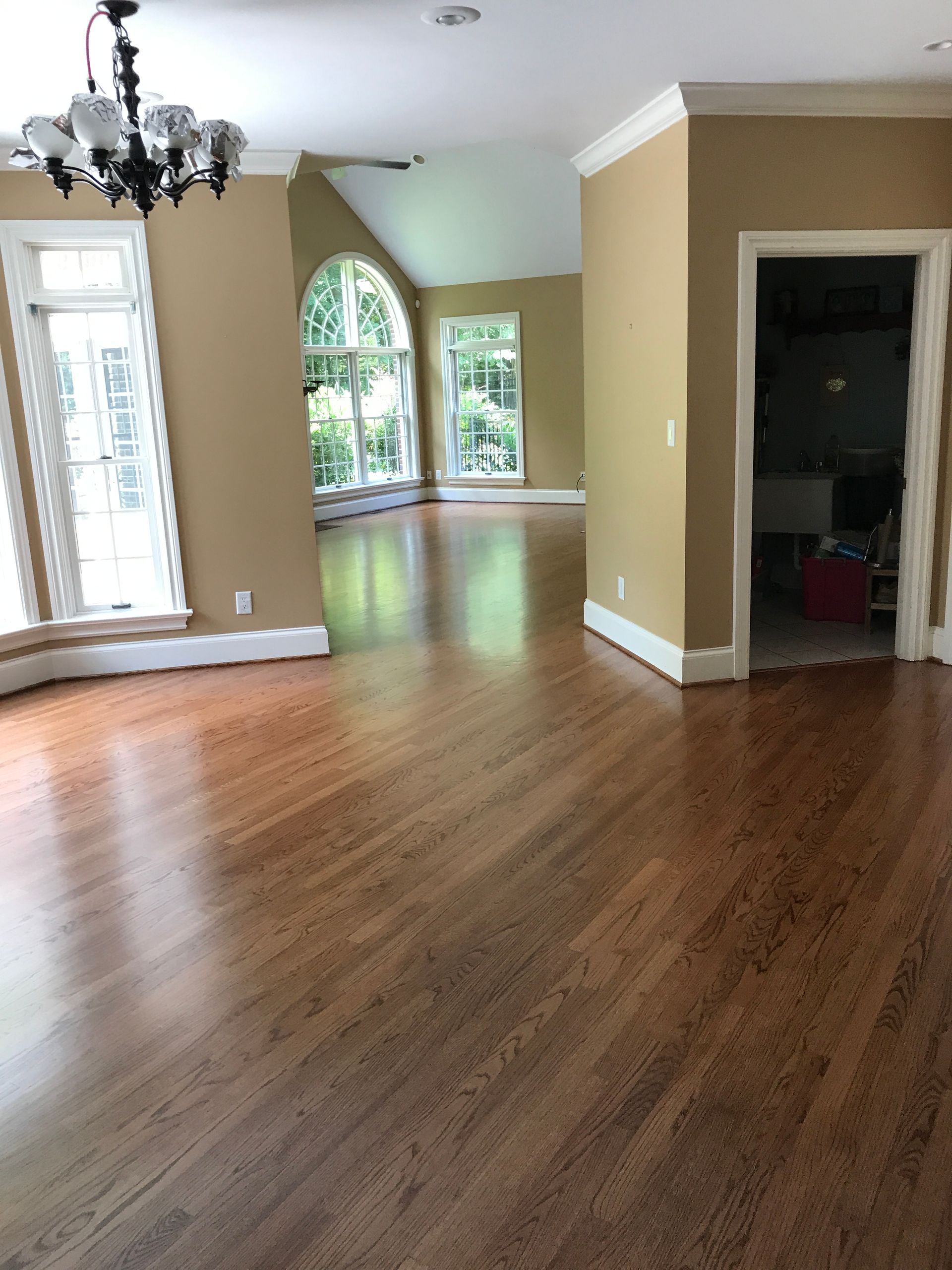 An empty living room with hardwood floors and a chandelier