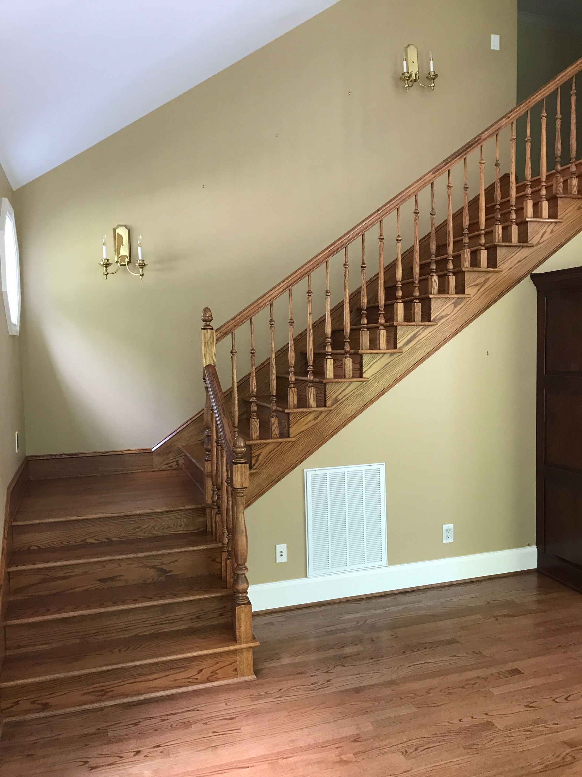 A wooden staircase in an empty room with tan walls