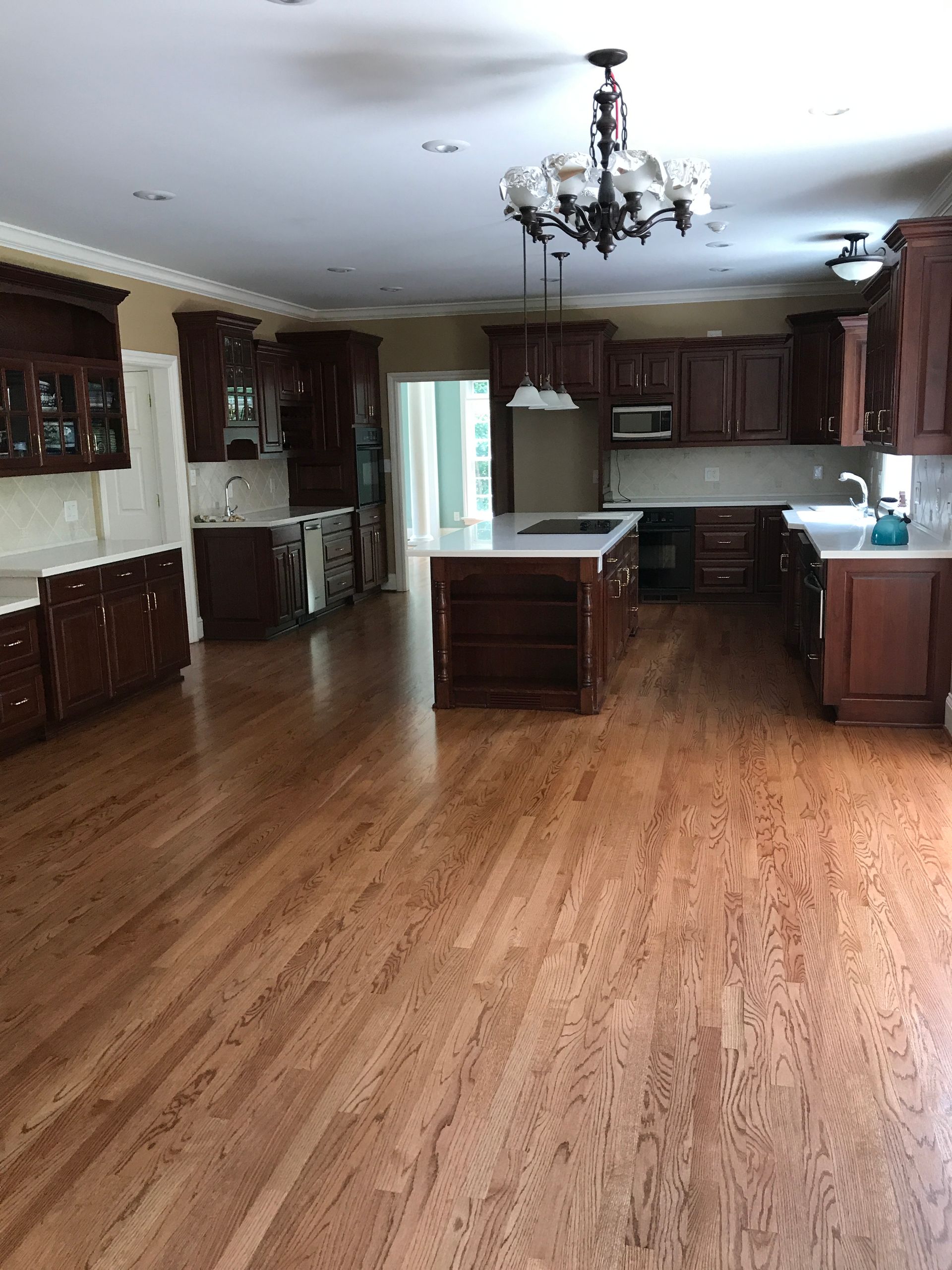 A large kitchen with hardwood floors and a chandelier hanging from the ceiling.