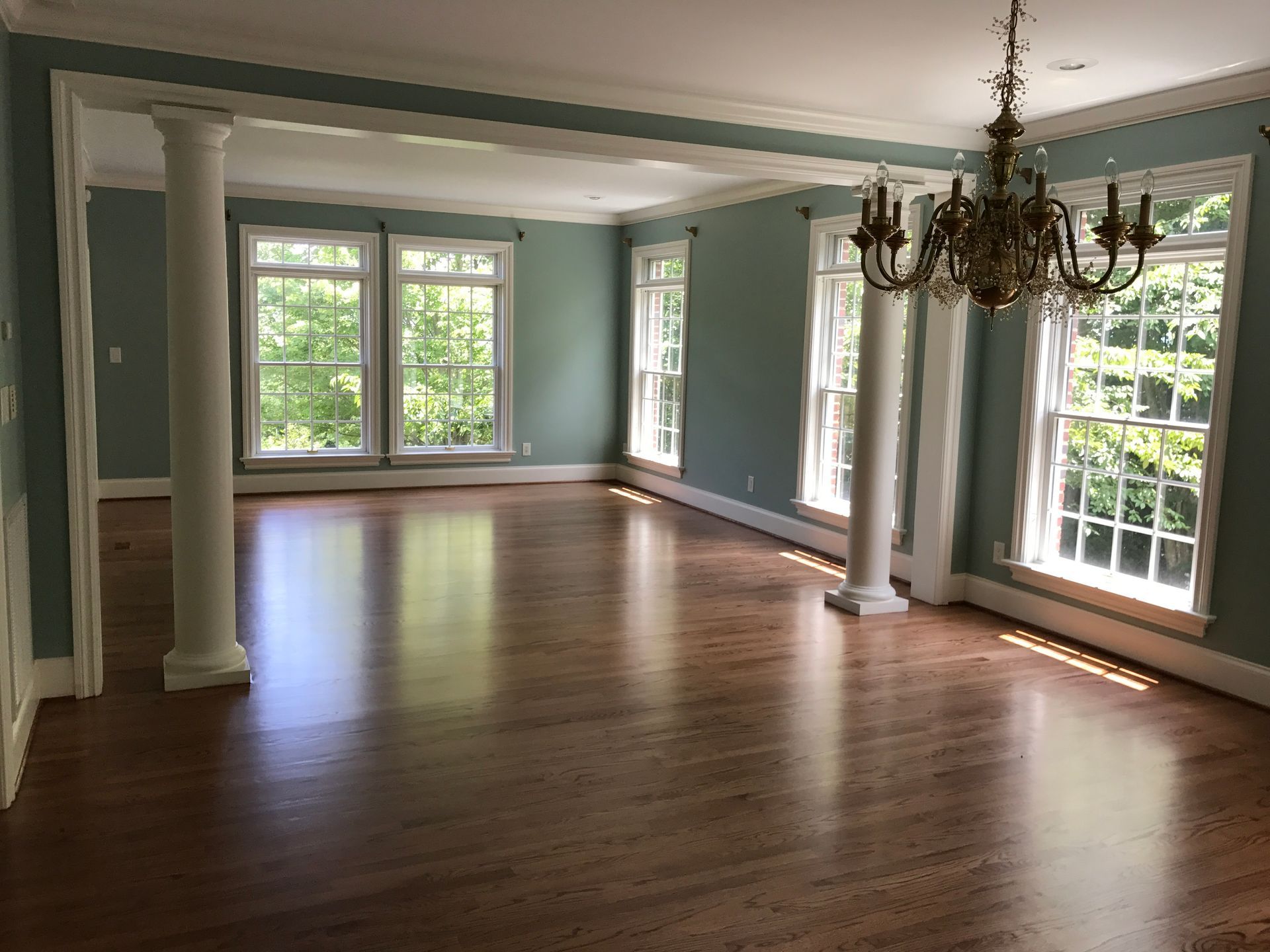 An empty living room with hardwood floors and a chandelier.