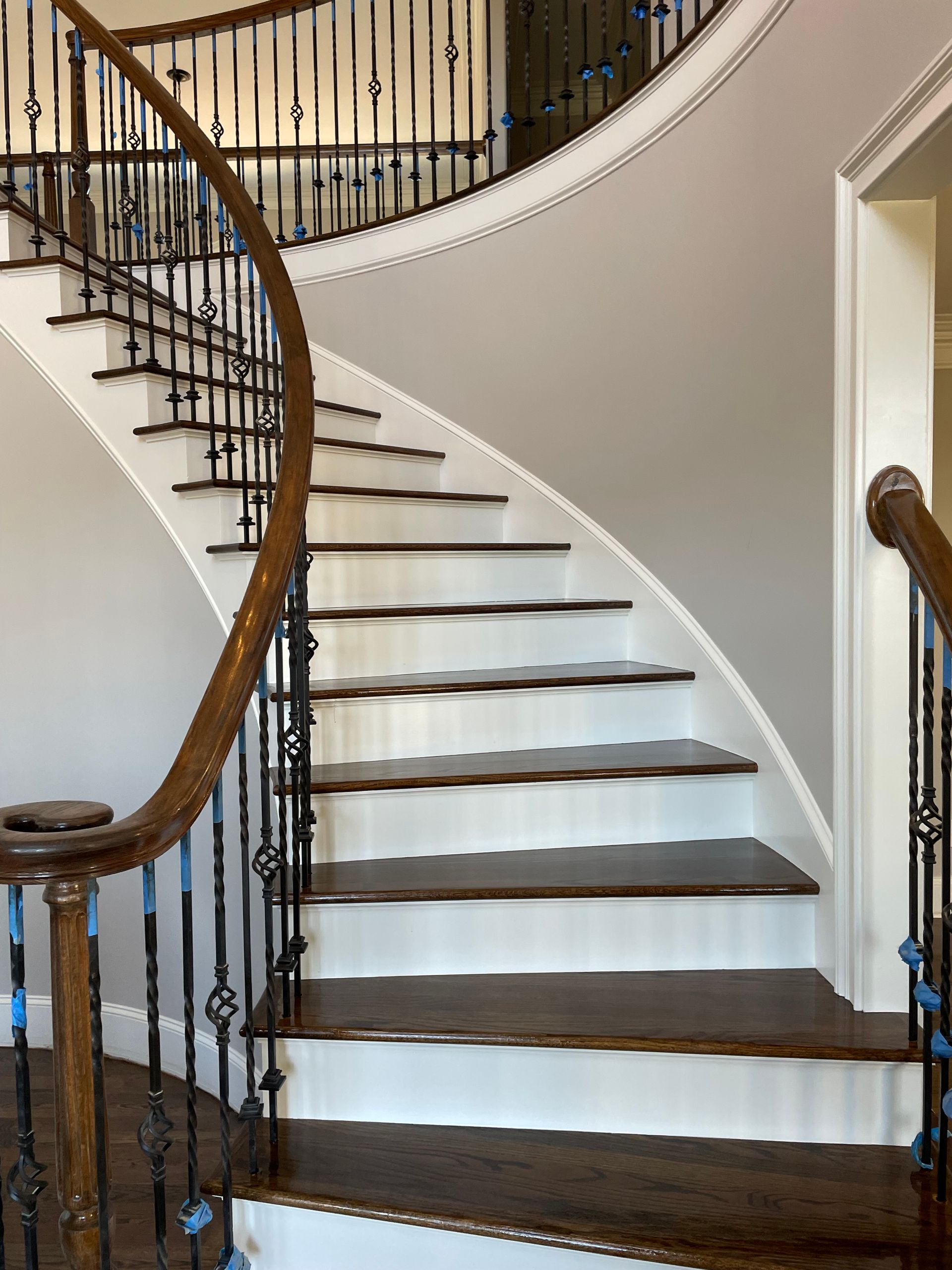 A curved staircase with white steps and a wrought iron railing