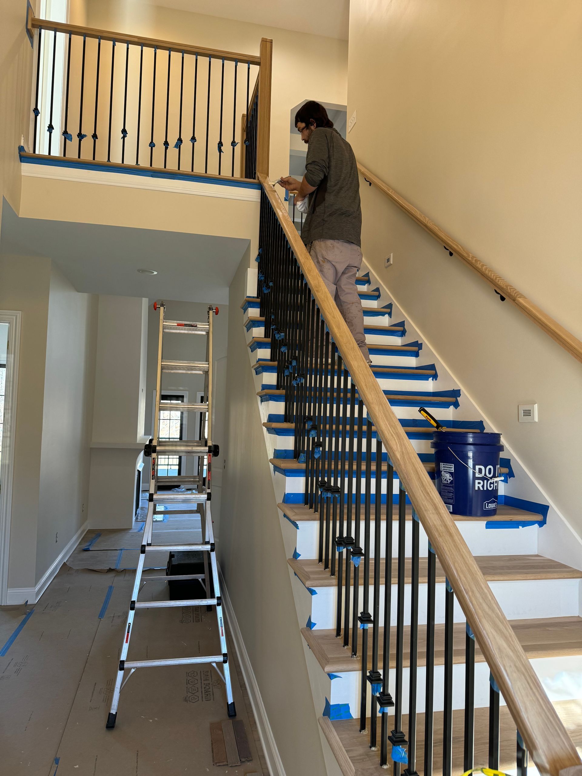 A man is painting a railing on a set of stairs.