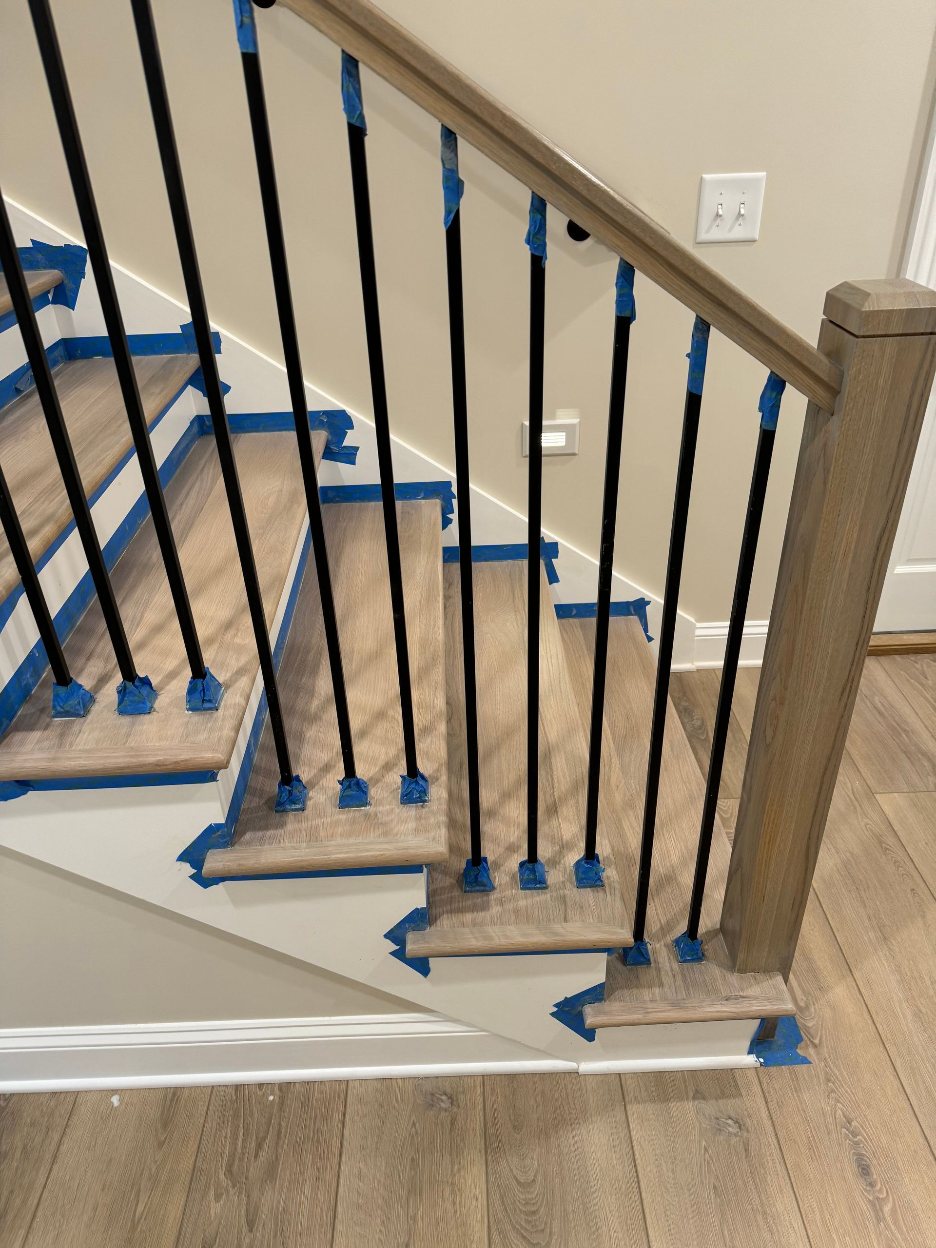 A wooden staircase with black railings is being painted blue.