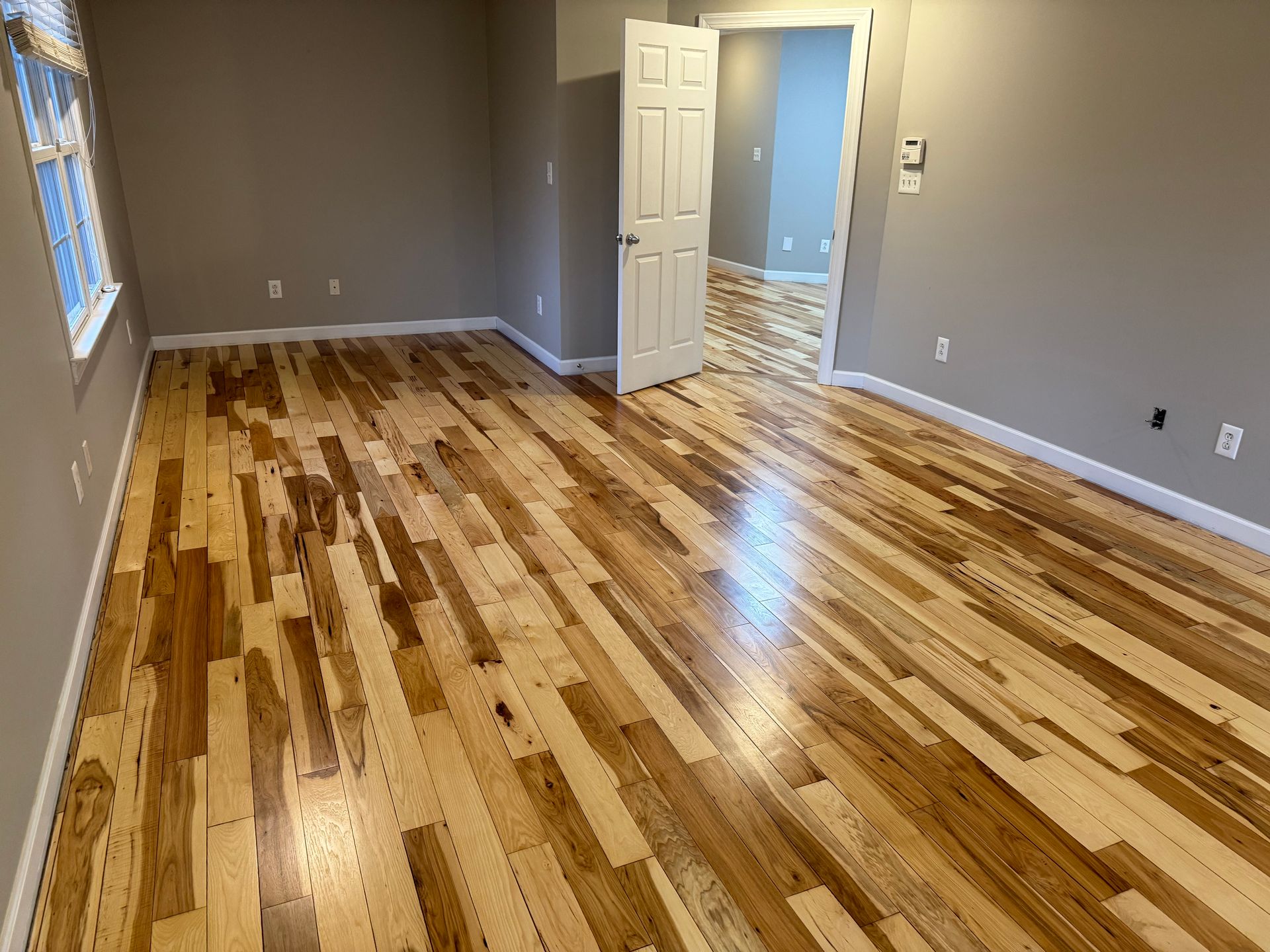 An empty room with hardwood floors and a door.