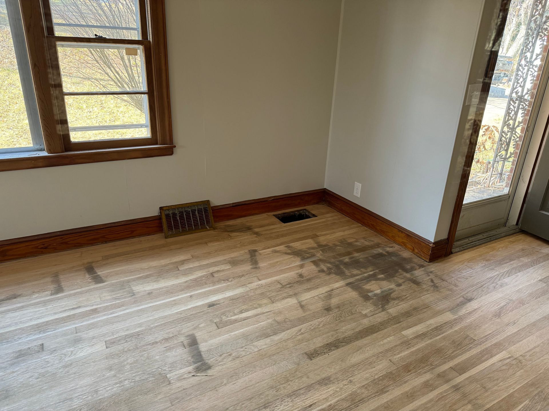 An empty room with hardwood floors and a window.